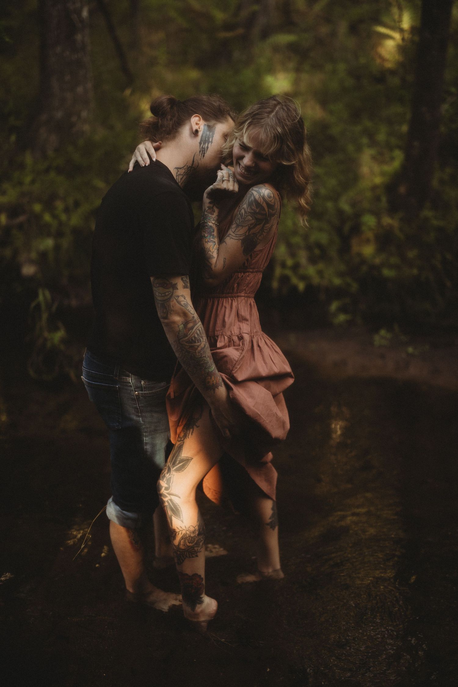 A couple embracing in a wooded area during golden hour.