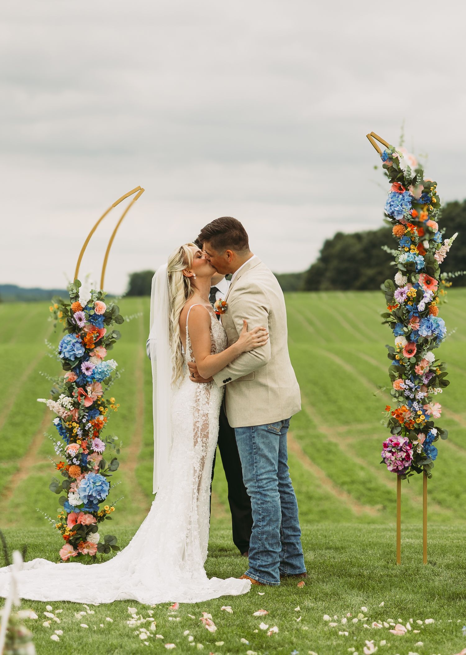 A romantic outdoor wedding ceremony with a beautiful floral arch and rolling green hills in the background.