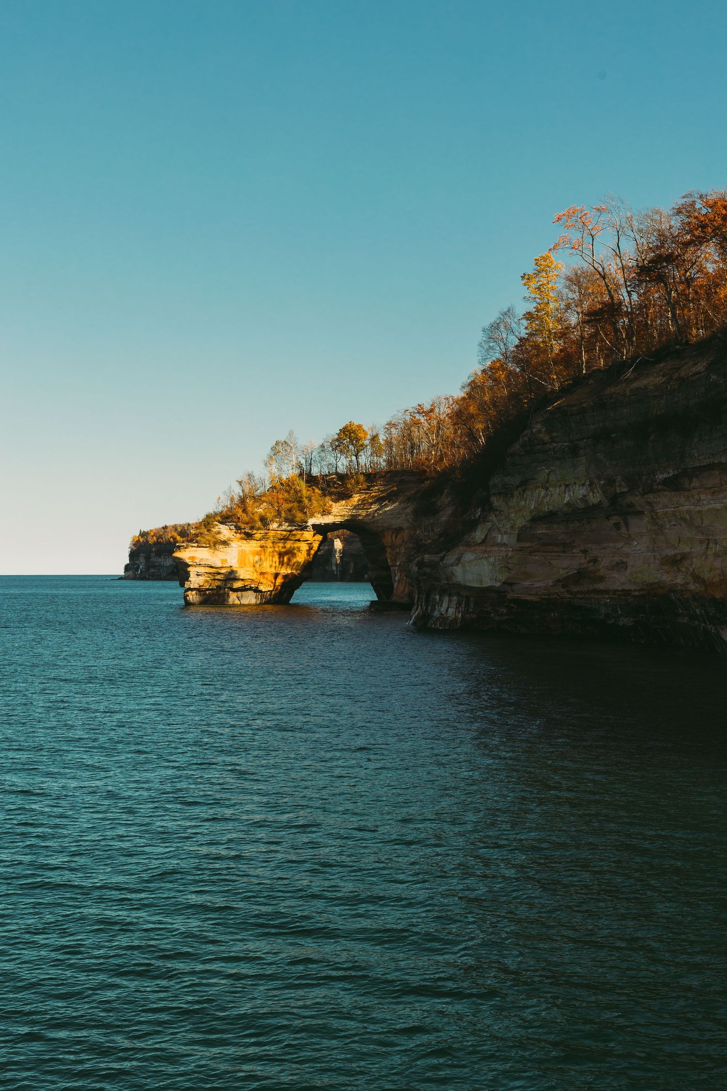 Scenic coastal landscape featuring dramatic limestone cliffs and clear blue waters of Lake Superior.