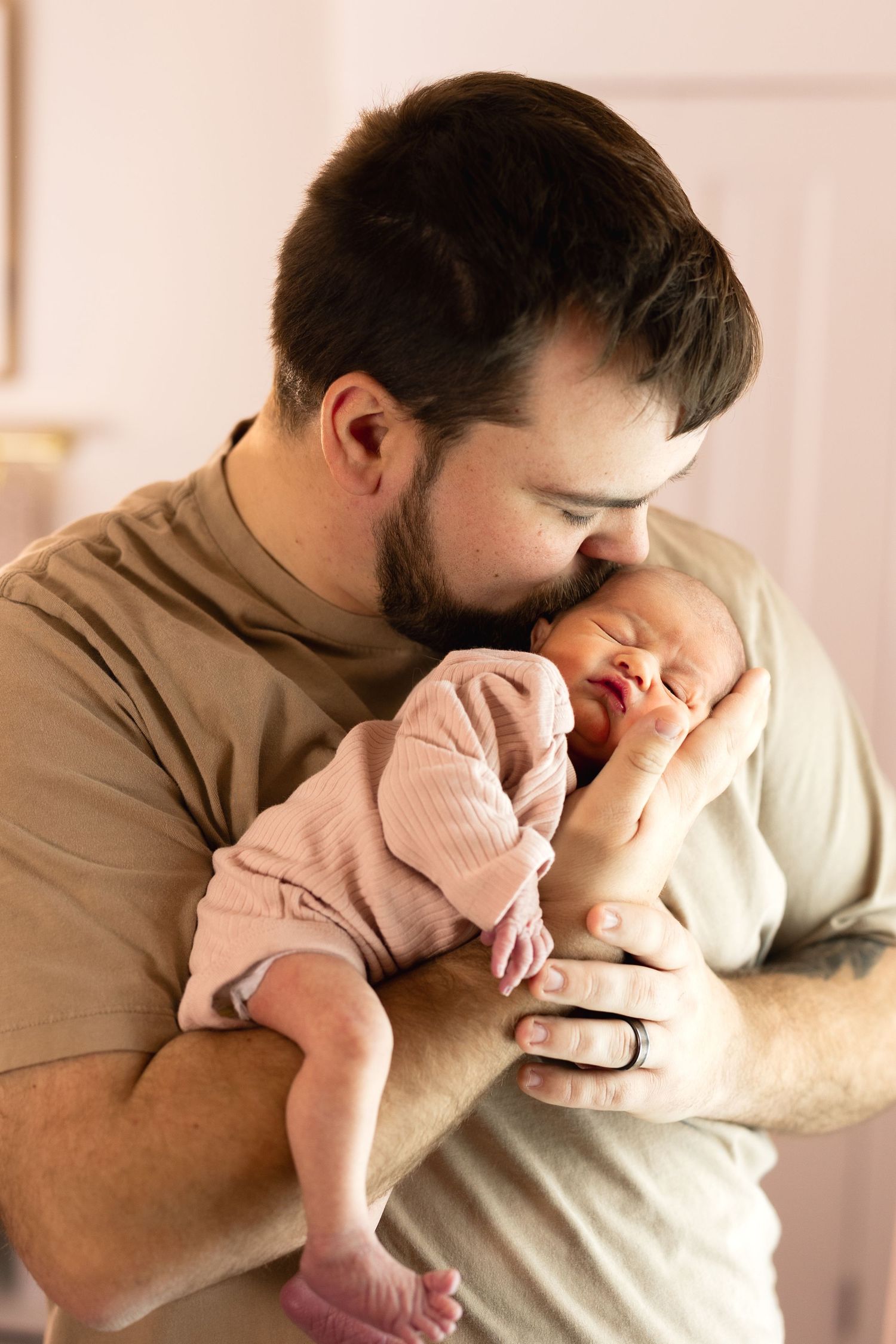 A tender moment between parent and newborn baby in soft indoor lighting.