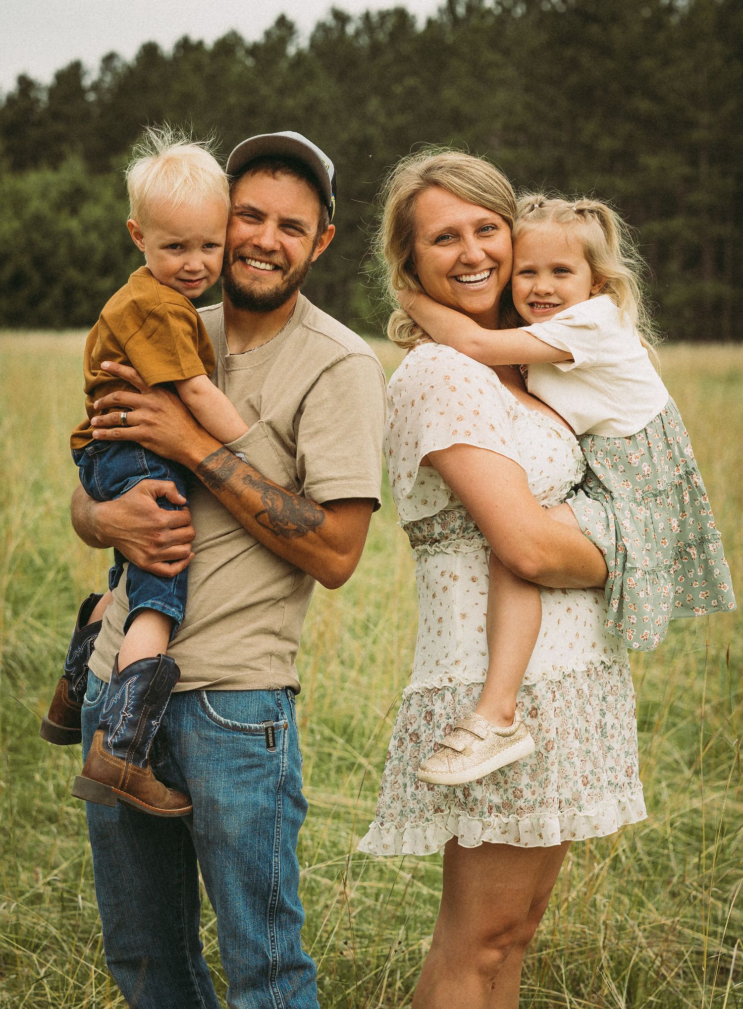 A family shares tender moments together in a grassy field during a golden hour photoshoot.