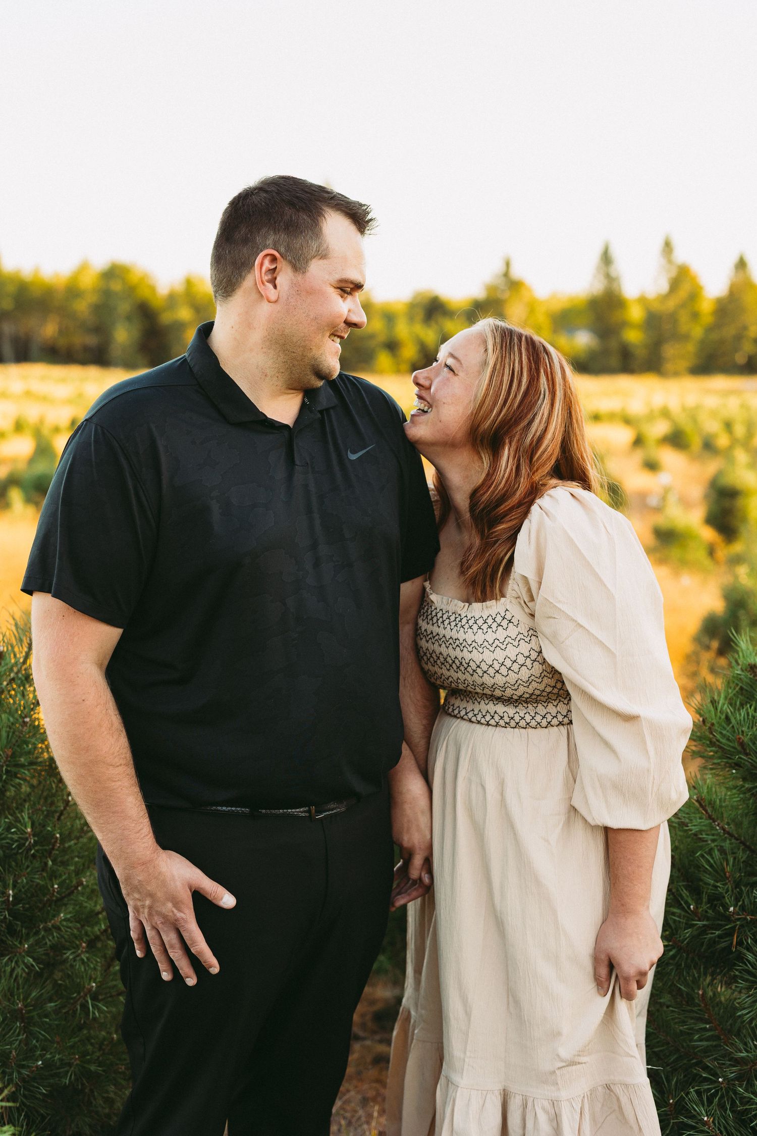 Couple sharing intimate moment in field during golden hour sunset.
