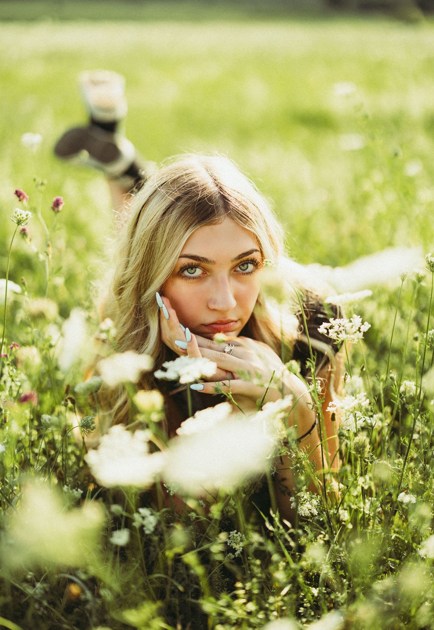 Portrait of a person lying in a blooming wildflower meadow on a sunny day.