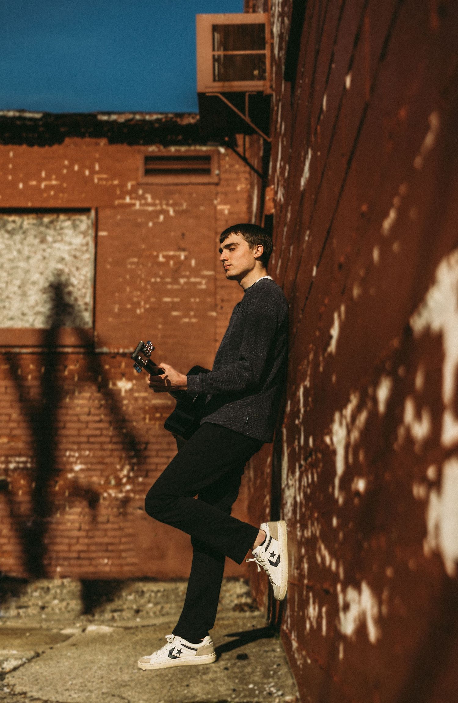 Artistic portrait series against rustic brick wall with dramatic shadows and lighting.