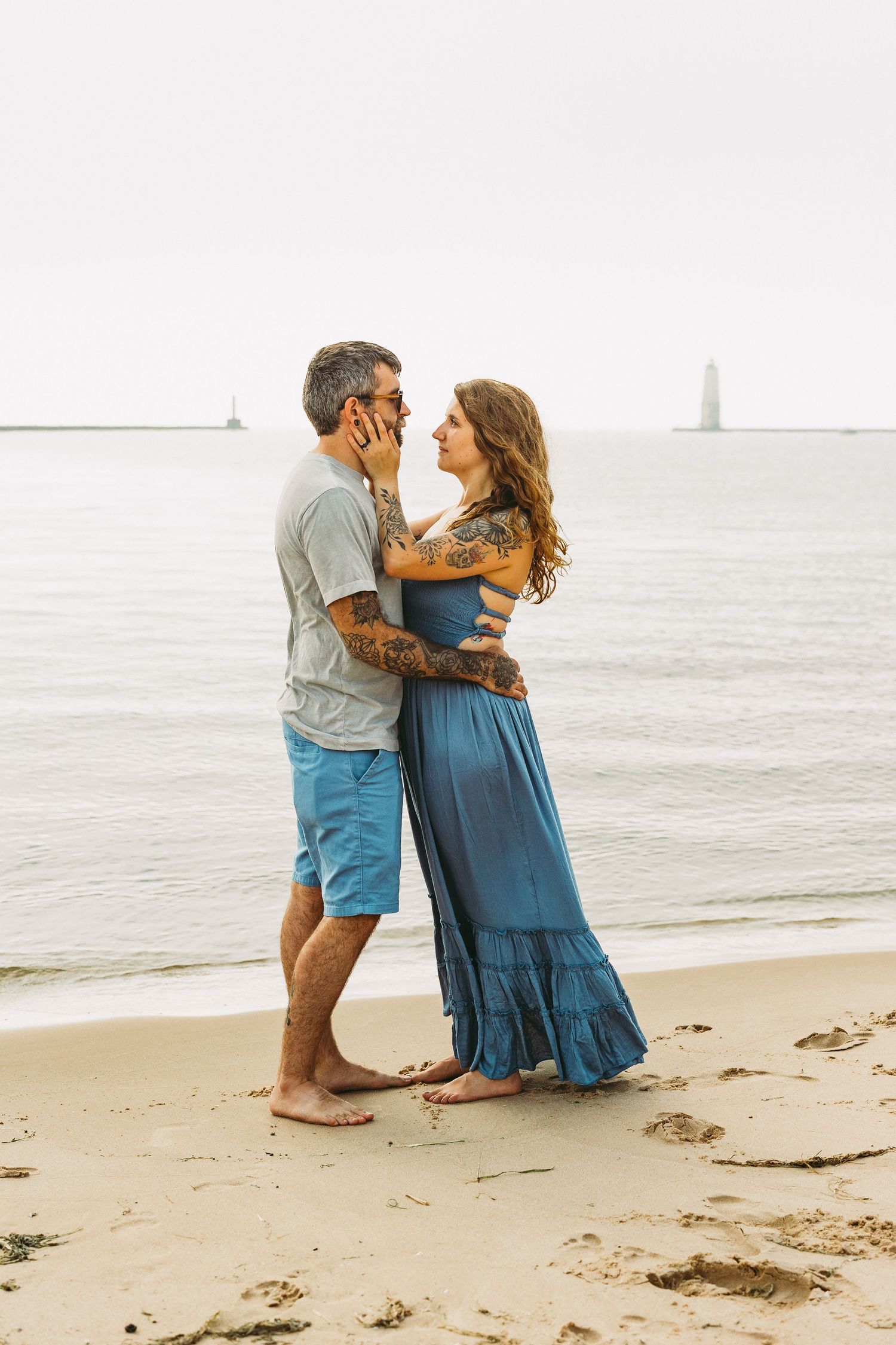 A couple shares an intimate moment while standing together on a peaceful beach at sunset.