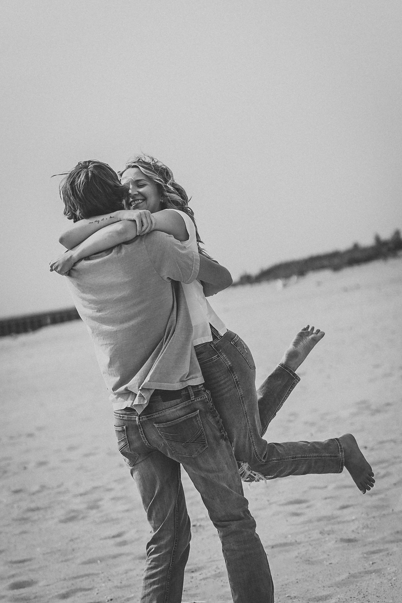 Black and white photos of a couple spinning and embracing on a beach with water in the background.