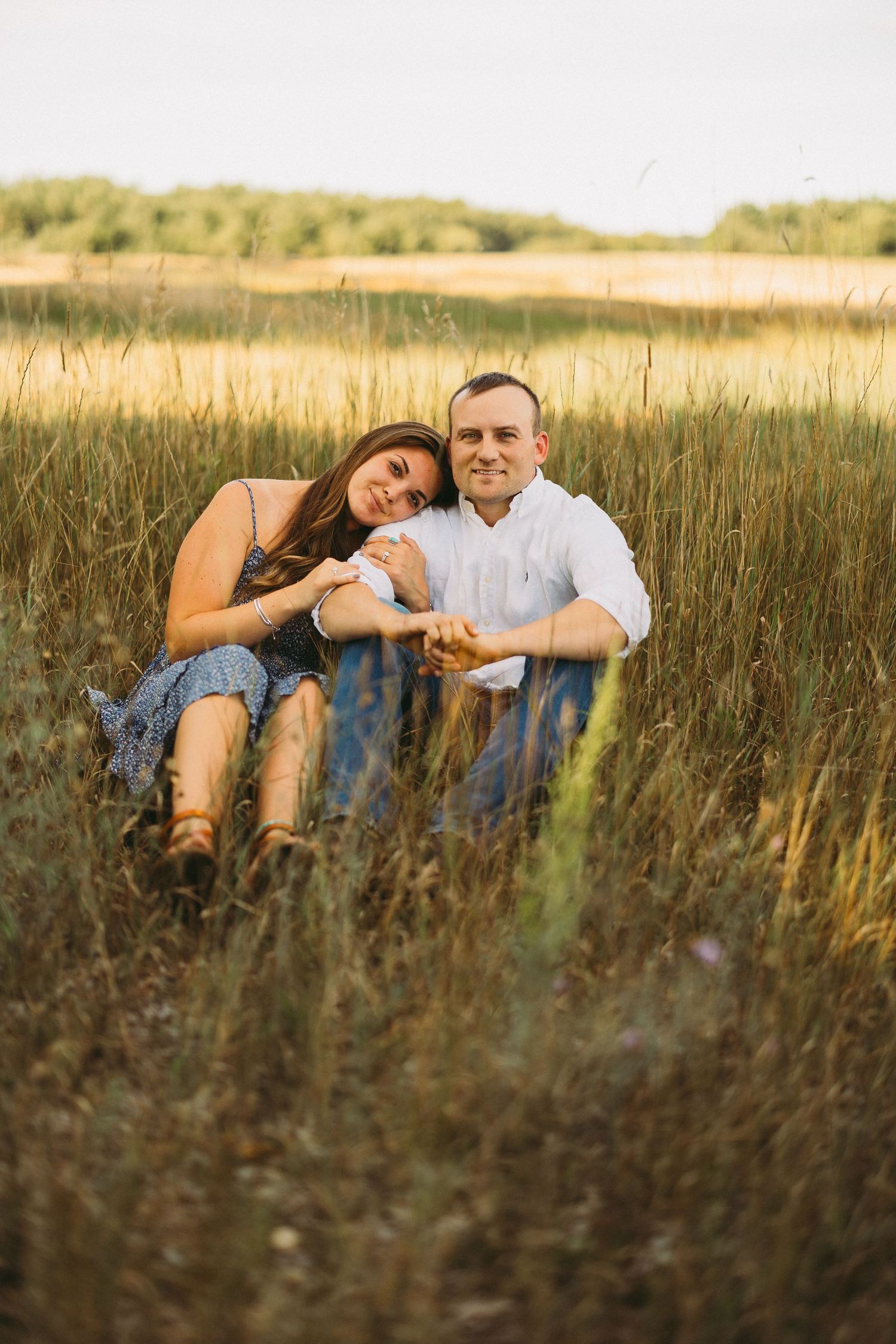 Couple relaxing together in a golden wheat field during sunset.