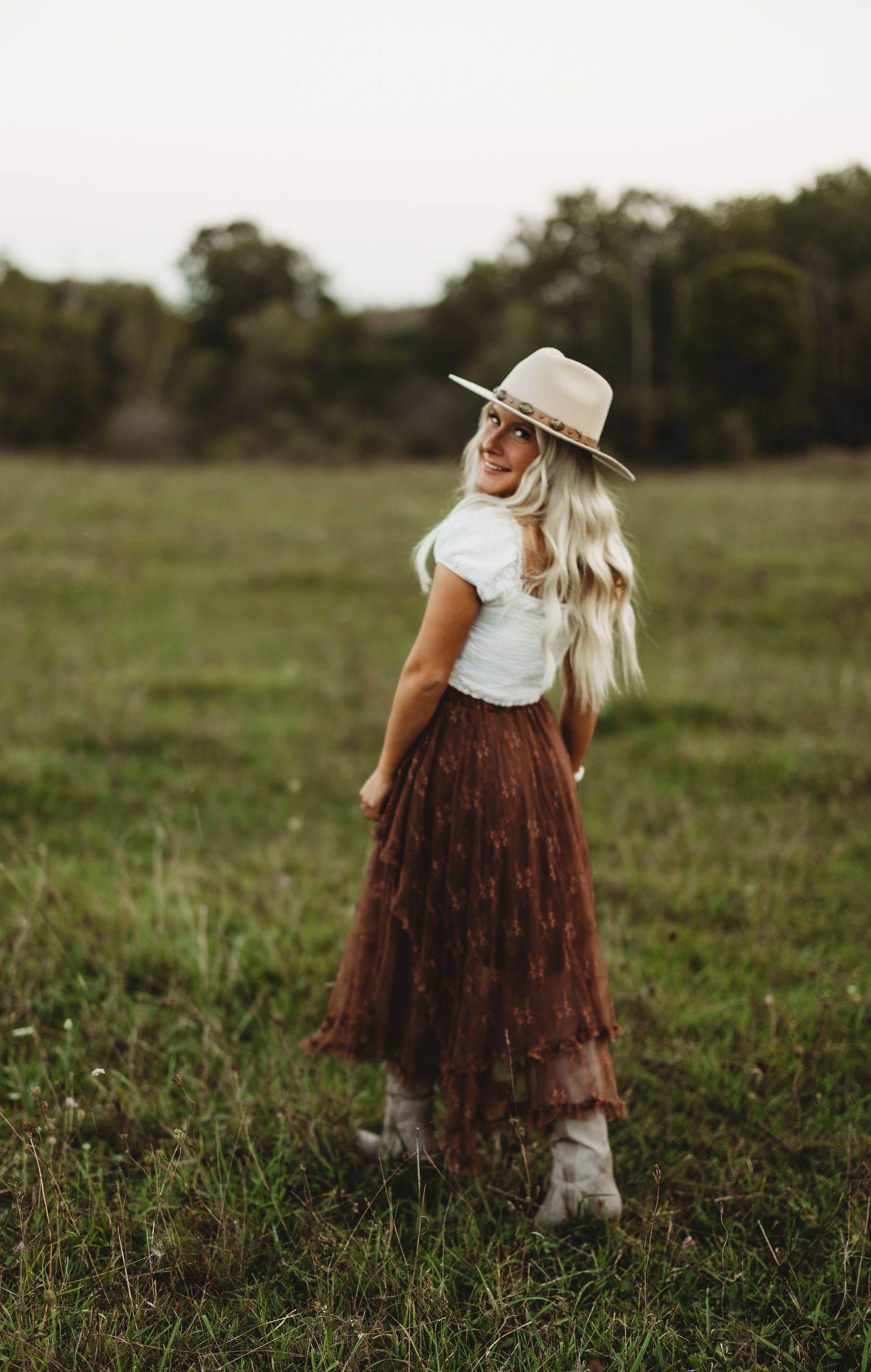Rustic country style portrait in a brown skirt and white top with hat.