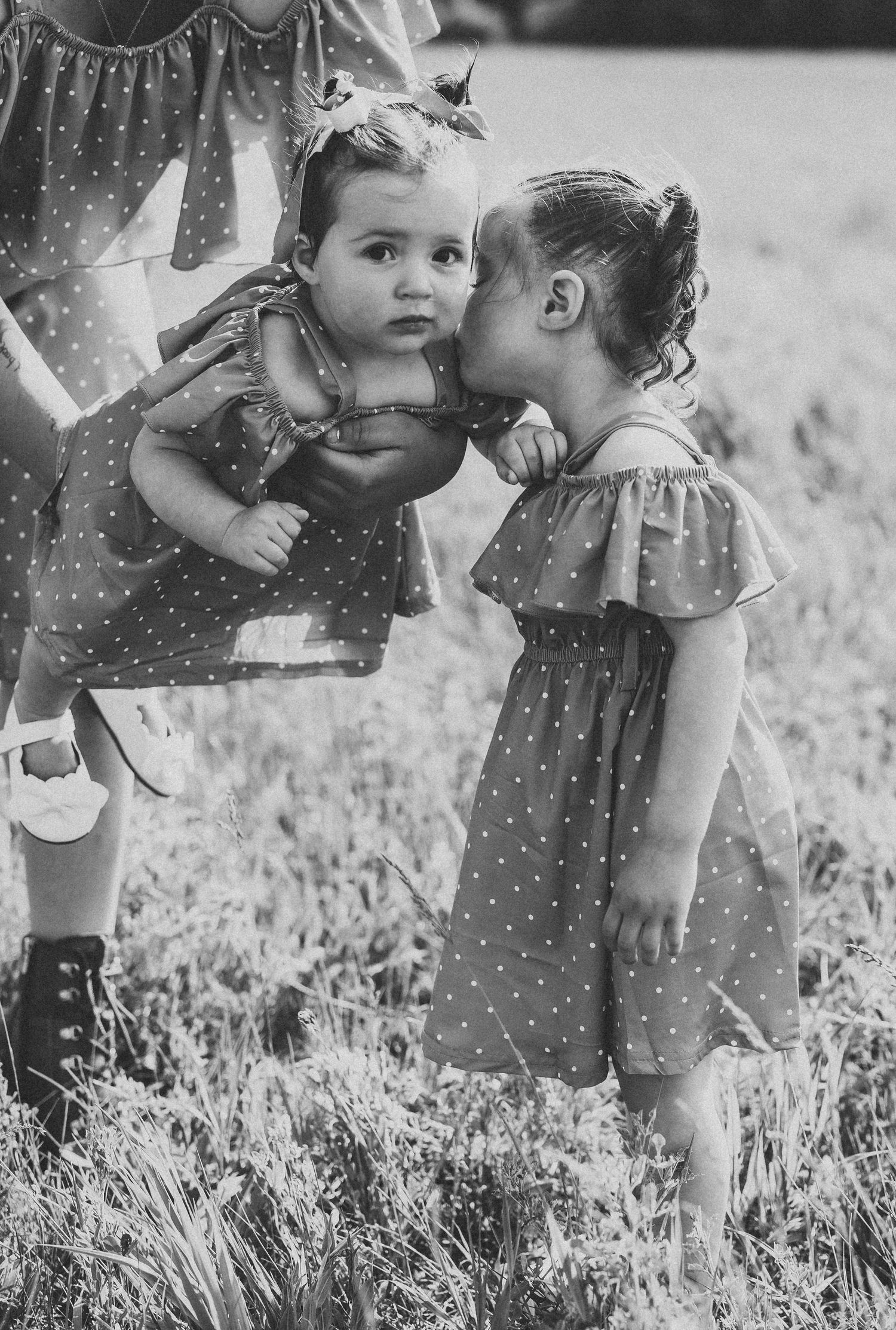 Black and white photo series showing a tender moment between a parent and child in a grassy field.