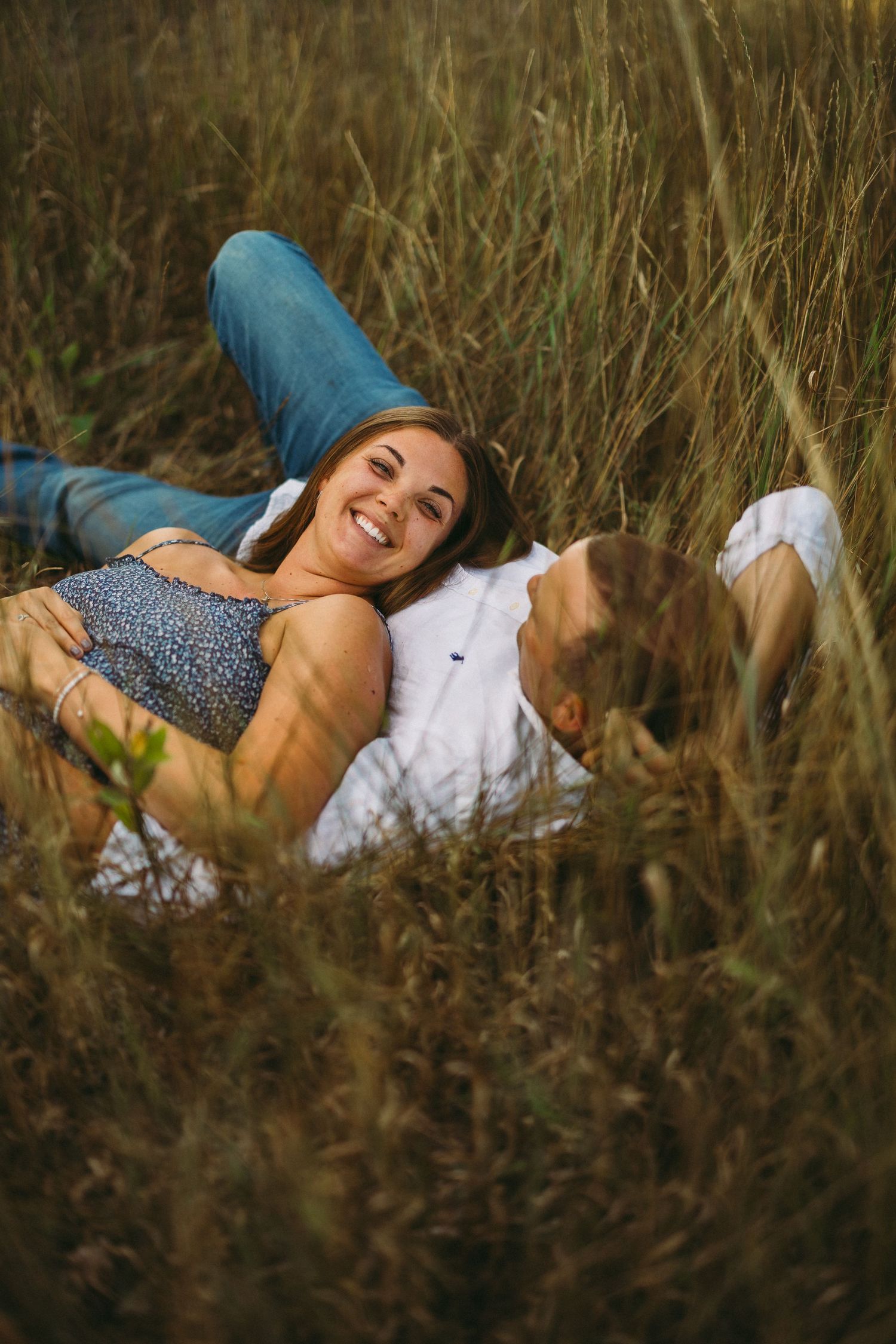 A series of candid outdoor portraits showing someone lying in tall grass wearing a patterned top and white pants.