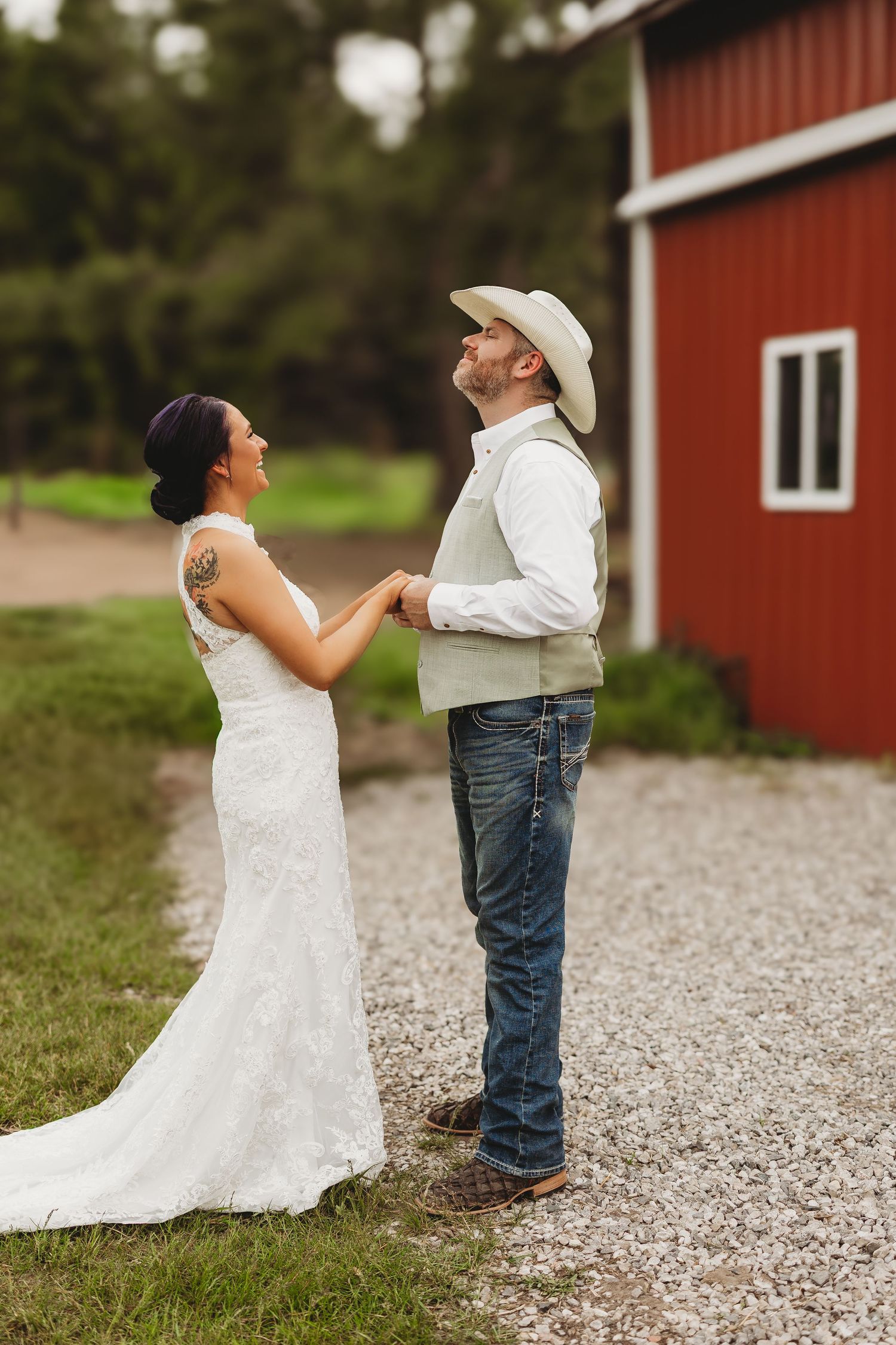 A couple in wedding attire playfully dance and twirl on a gravel path beside a red barn in a romantic photo sequence.