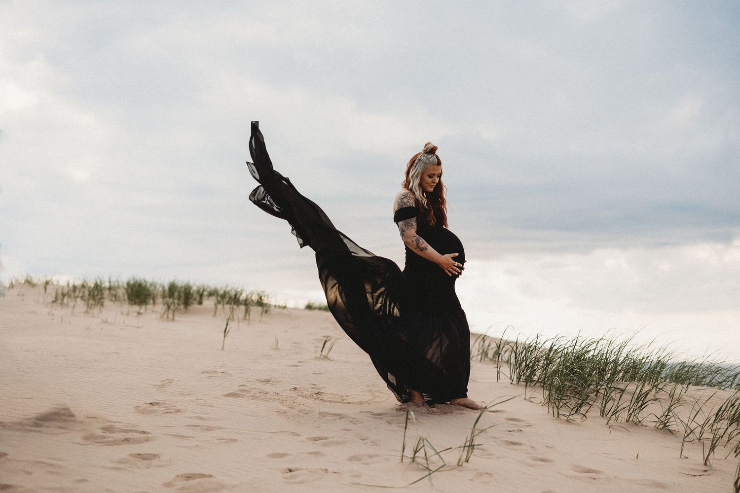 A silhouette of a dancer in black dress leaping gracefully on sand dunes.