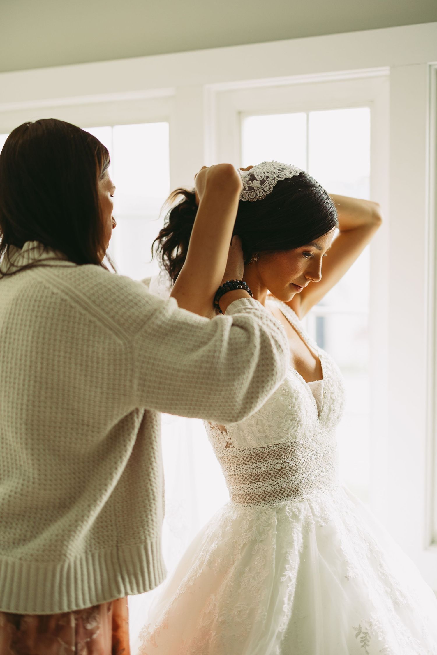 Behind the scenes of wedding dress preparation by window light.