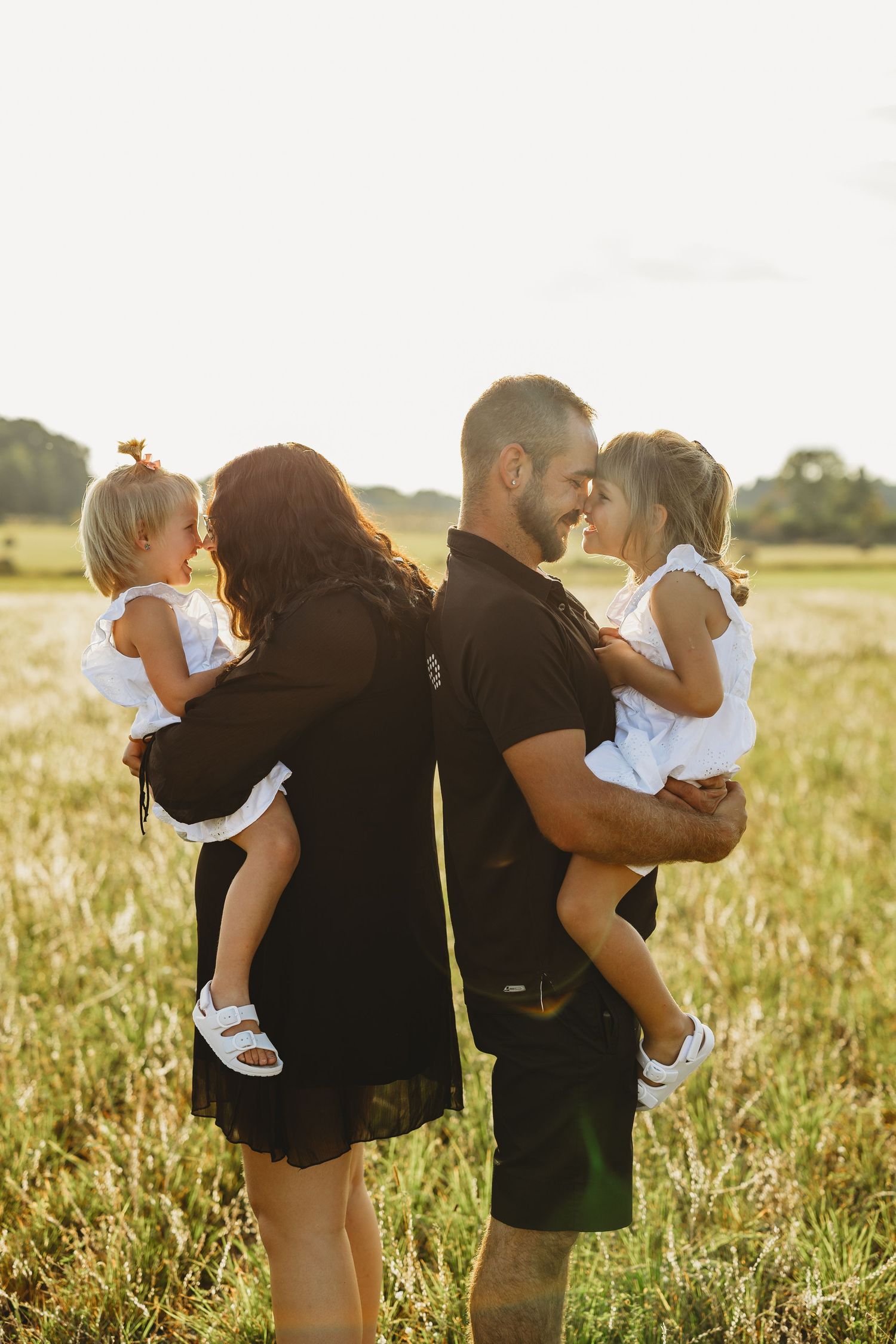 Silhouetted figures embracing in a sunlit field during golden hour.