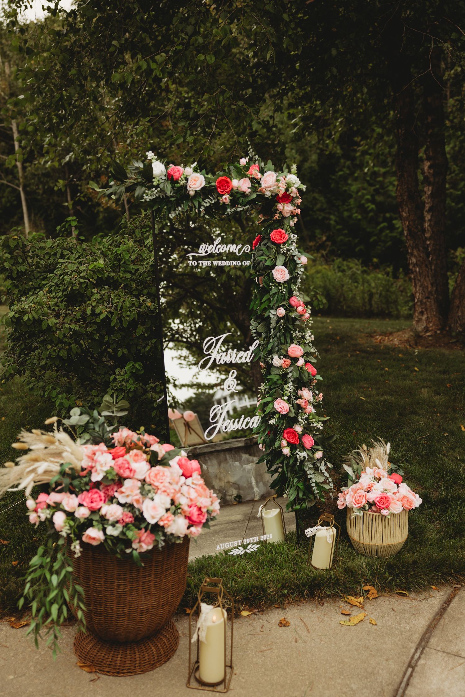 Elegant wedding welcome sign with pink floral arrangements, candles, and greenery backdrop for Jarred and Jessica.