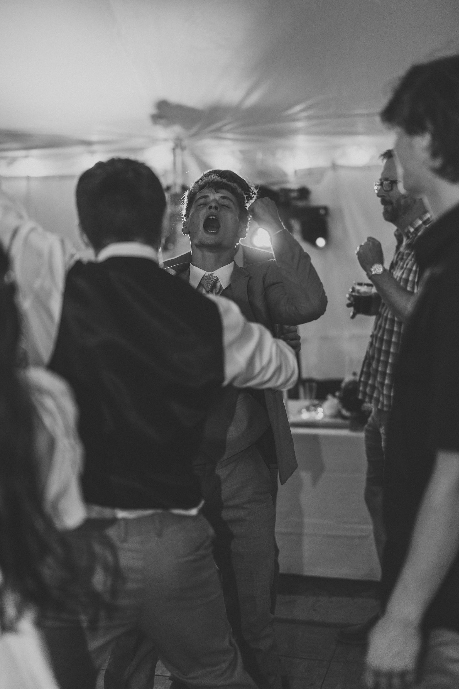 Black and white photo of wedding guests dancing at reception.