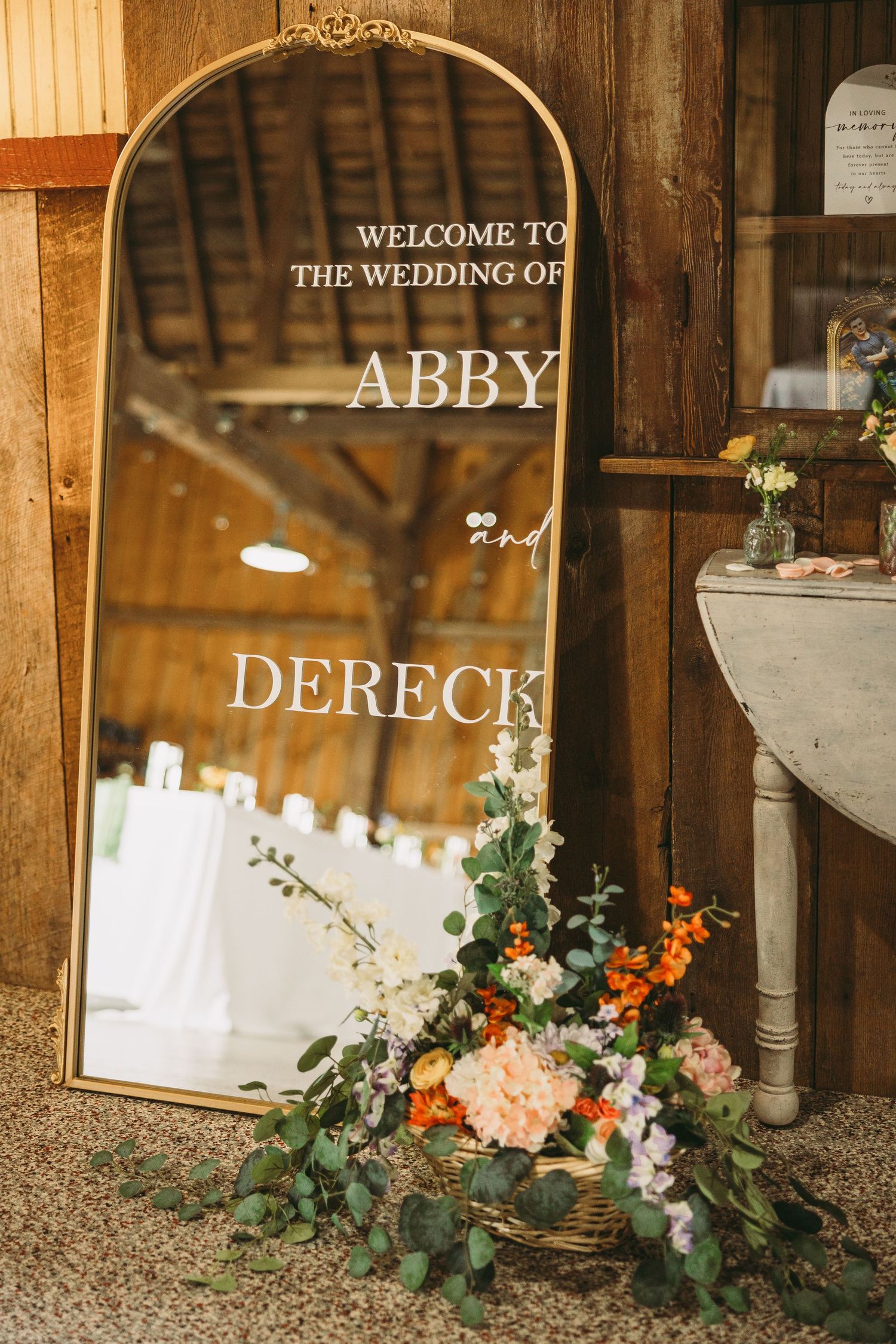 Rustic barn wedding venue entrance decorated with floral arrangements and welcome signage.
