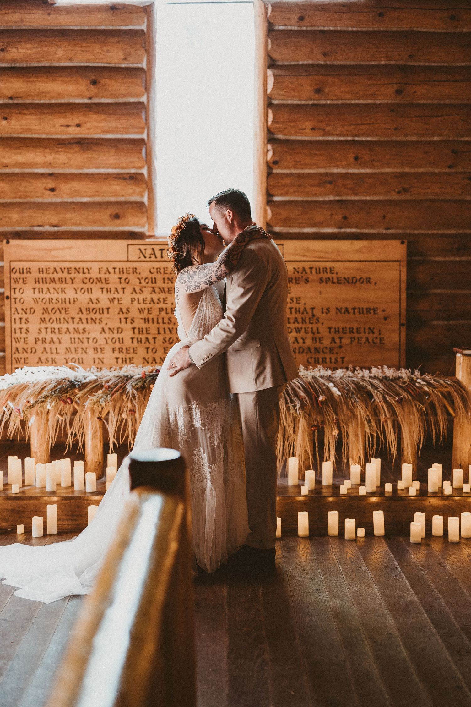 A romantic couple shares a dance in a rustic wooden barn venue with sunlit windows and vintage decor.