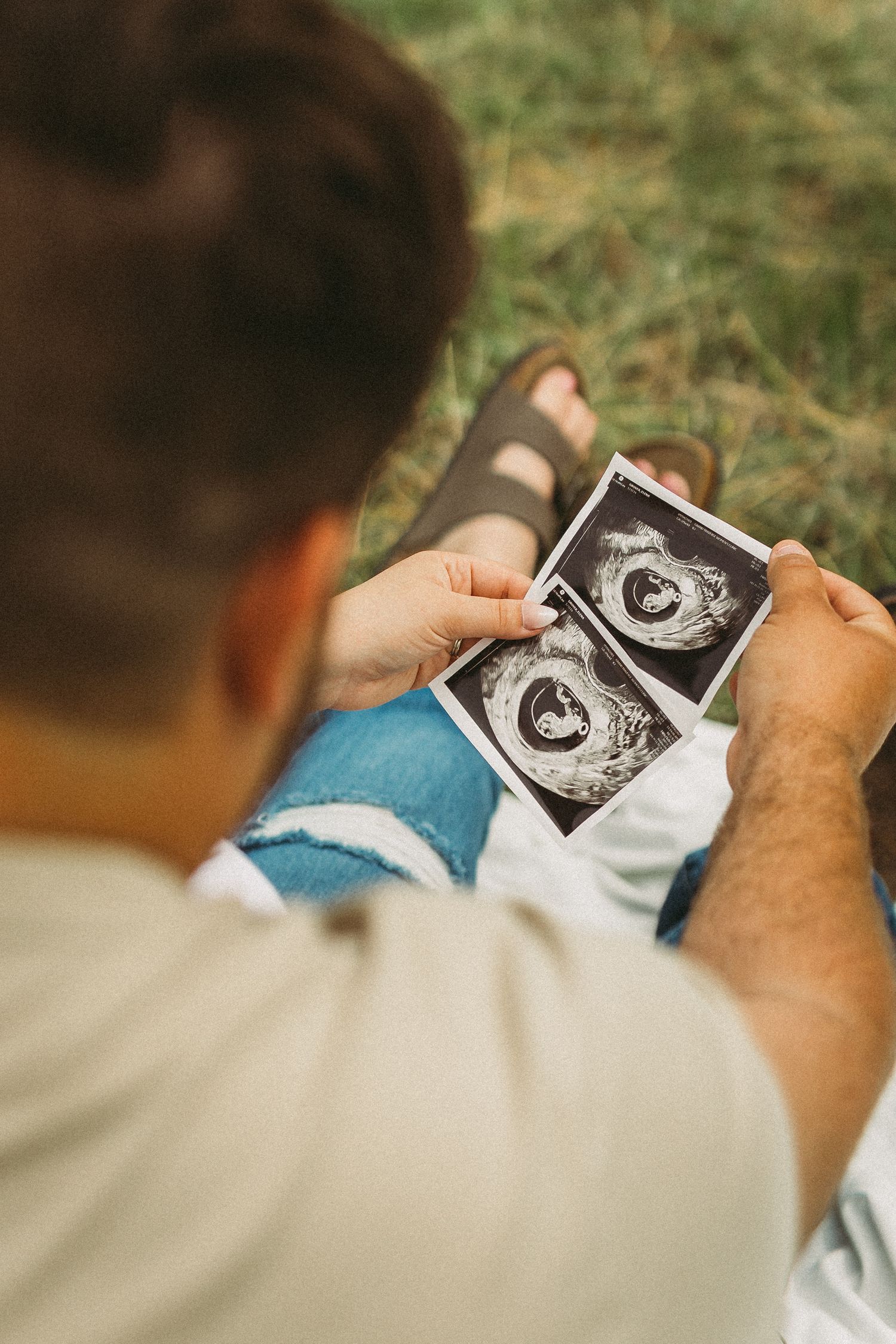 Person holding and looking at ultrasound images outdoors in natural lighting.
