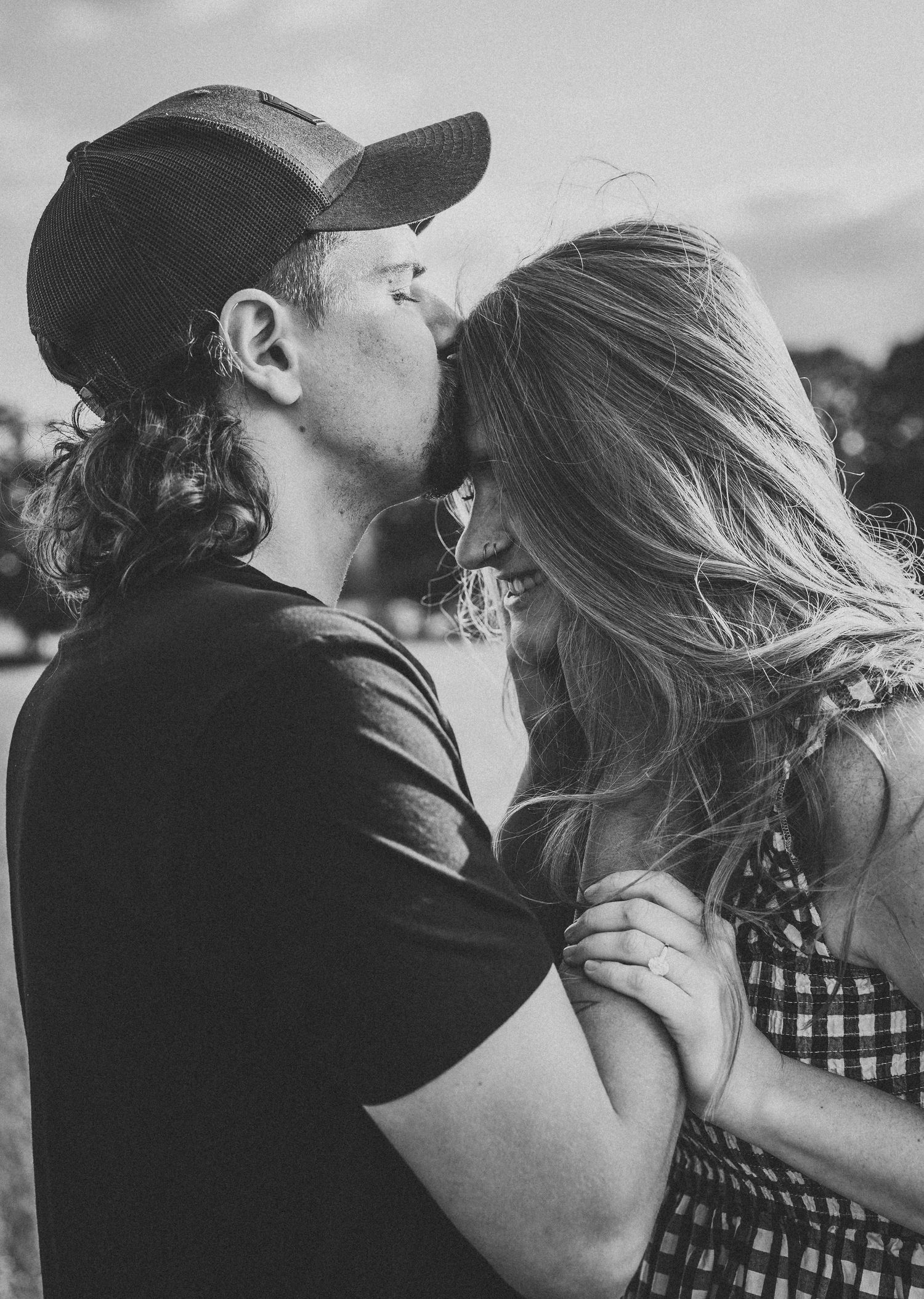 A romantic black and white photo sequence showing a couple embracing and kissing against a railing outdoors.
