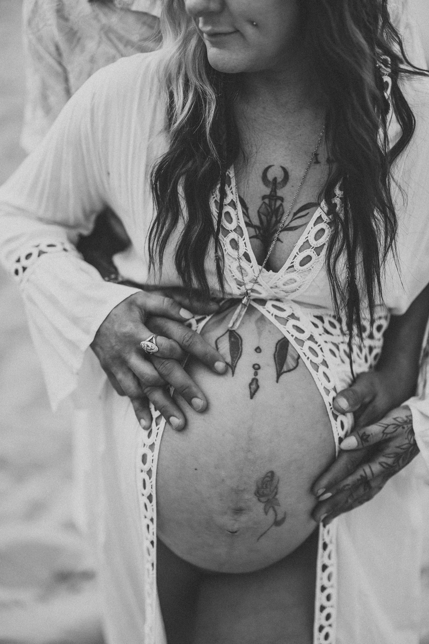 Artistic black and white photo of pregnant woman with henna designs on belly.