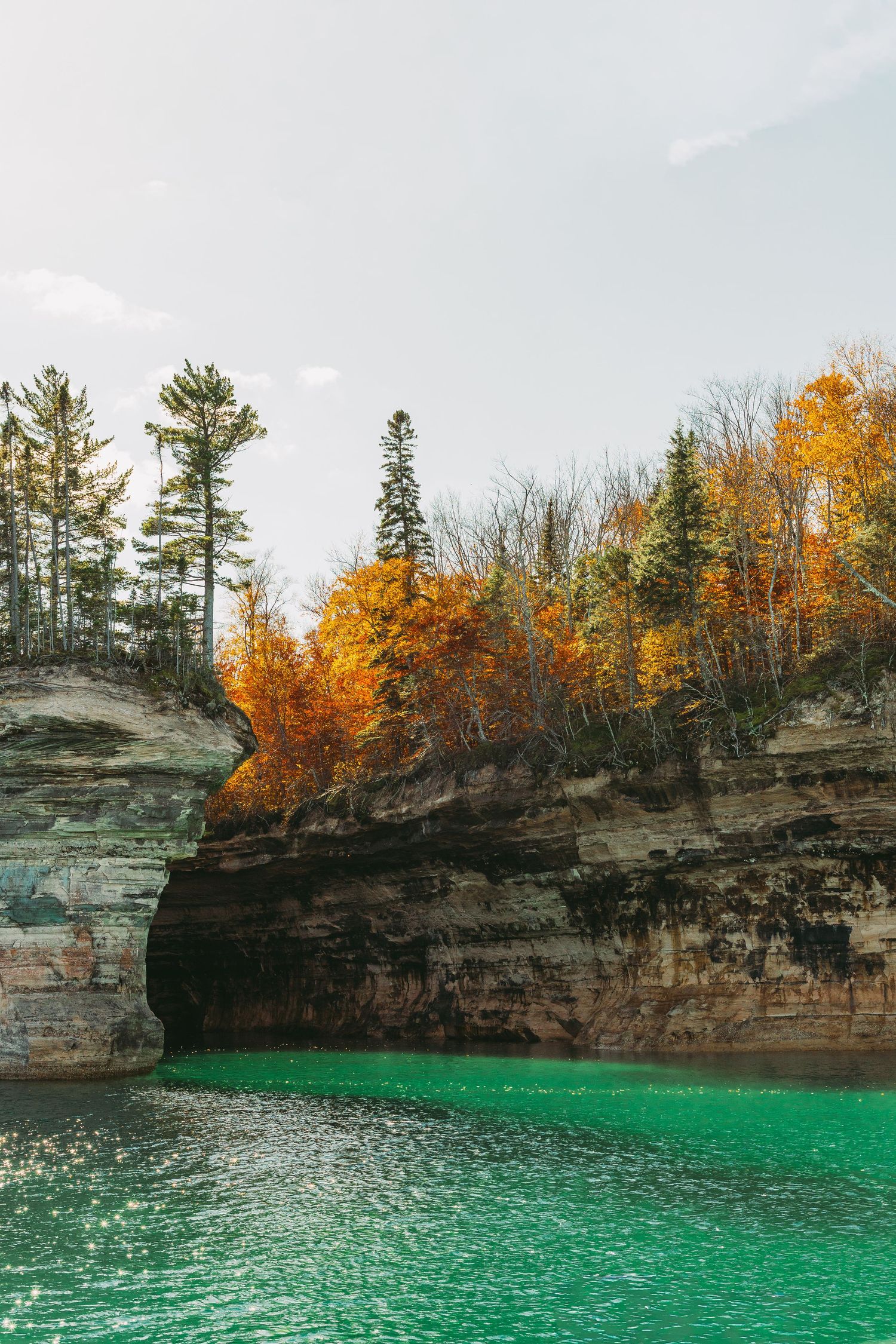 Turquoise waters meet dramatic limestone cliffs topped with colorful fall trees.