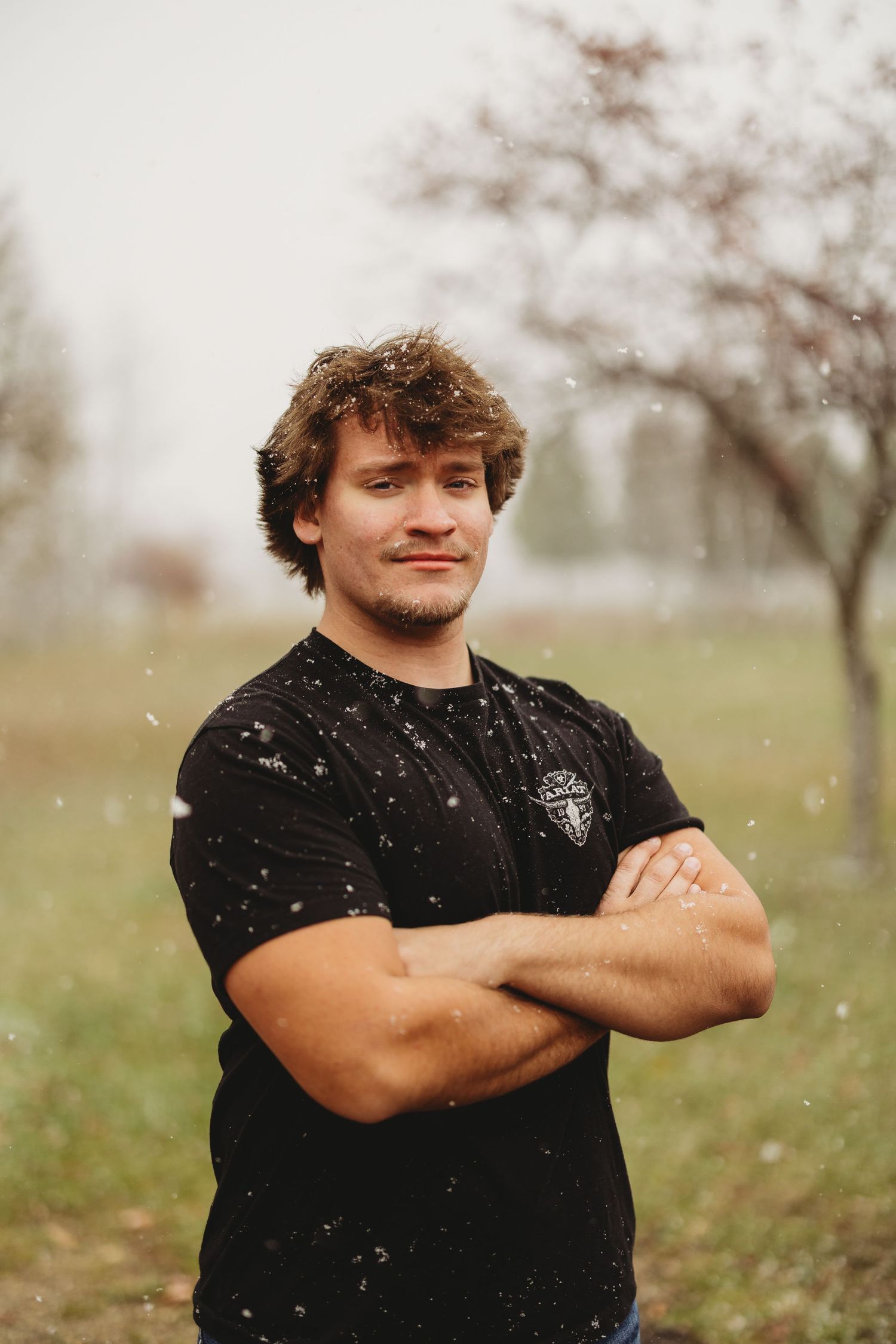 Person in black t-shirt standing outdoors with arms crossed.