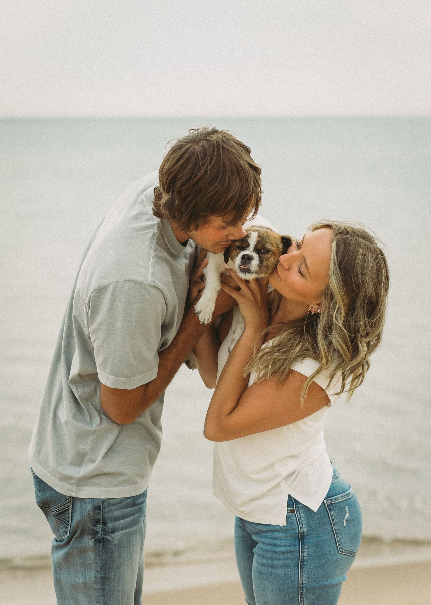 Sweet interaction between couple and small dog at the beach.