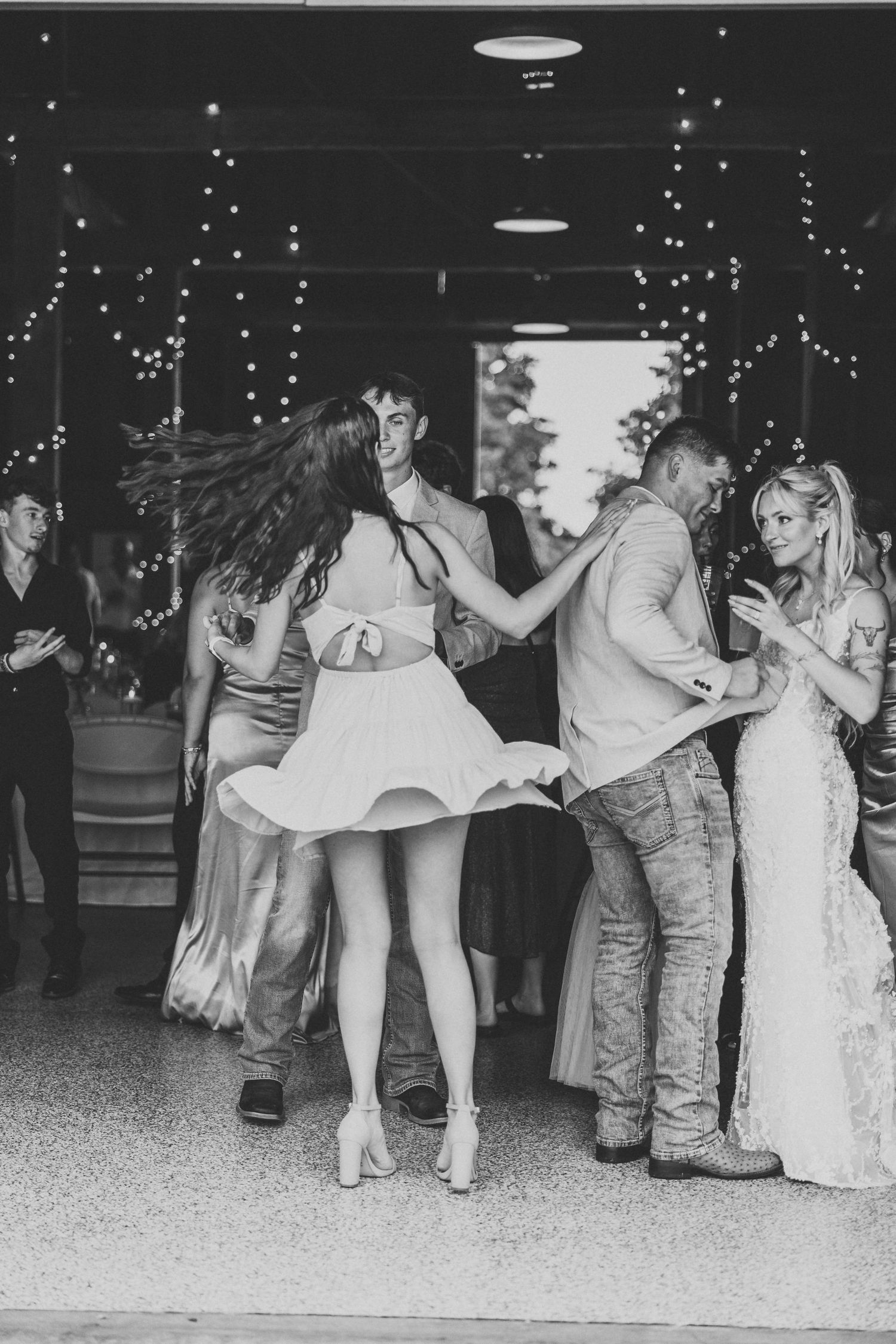 Wedding couple performing fun dance moves on the reception floor in black and white.