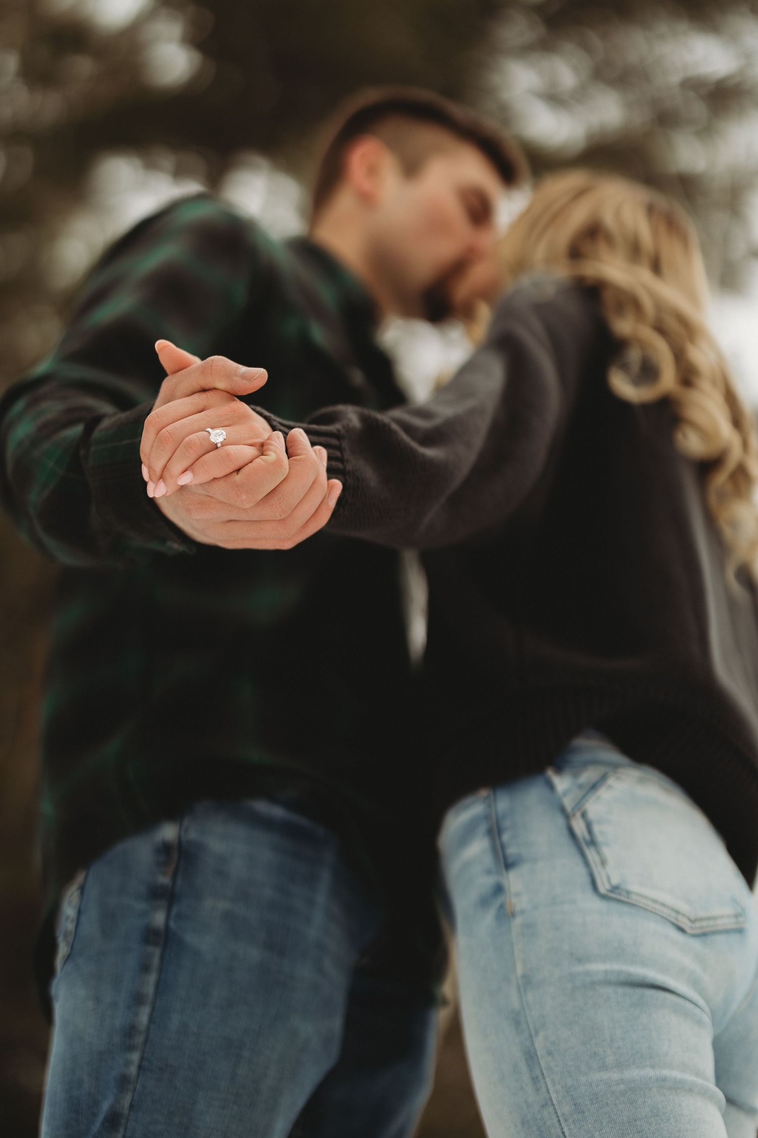 A couple in jeans and dark clothing embrace while dancing together in a romantic pose.