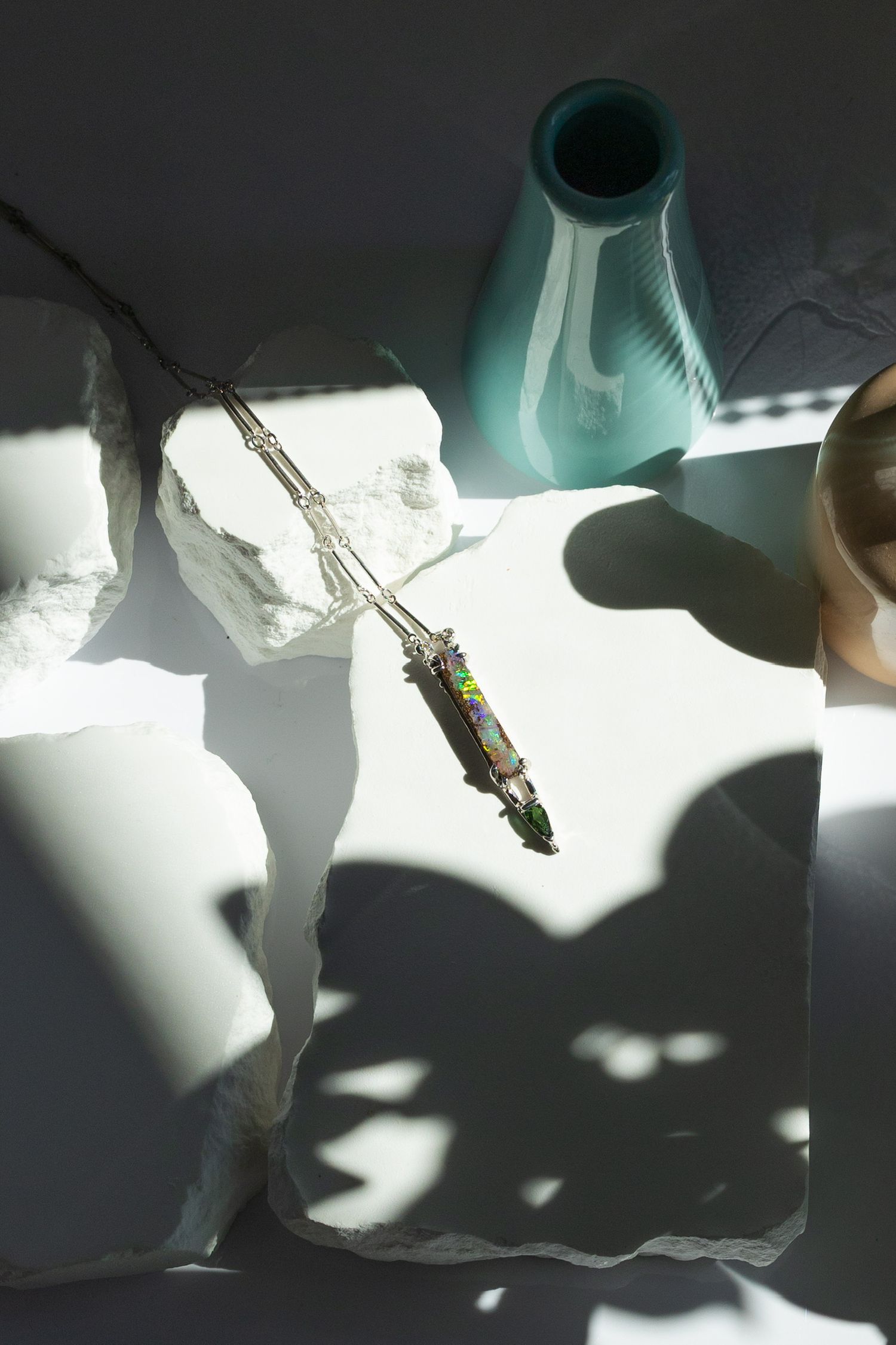 Crystal pendant necklace casting dramatic shadows in artistic lighting setup.