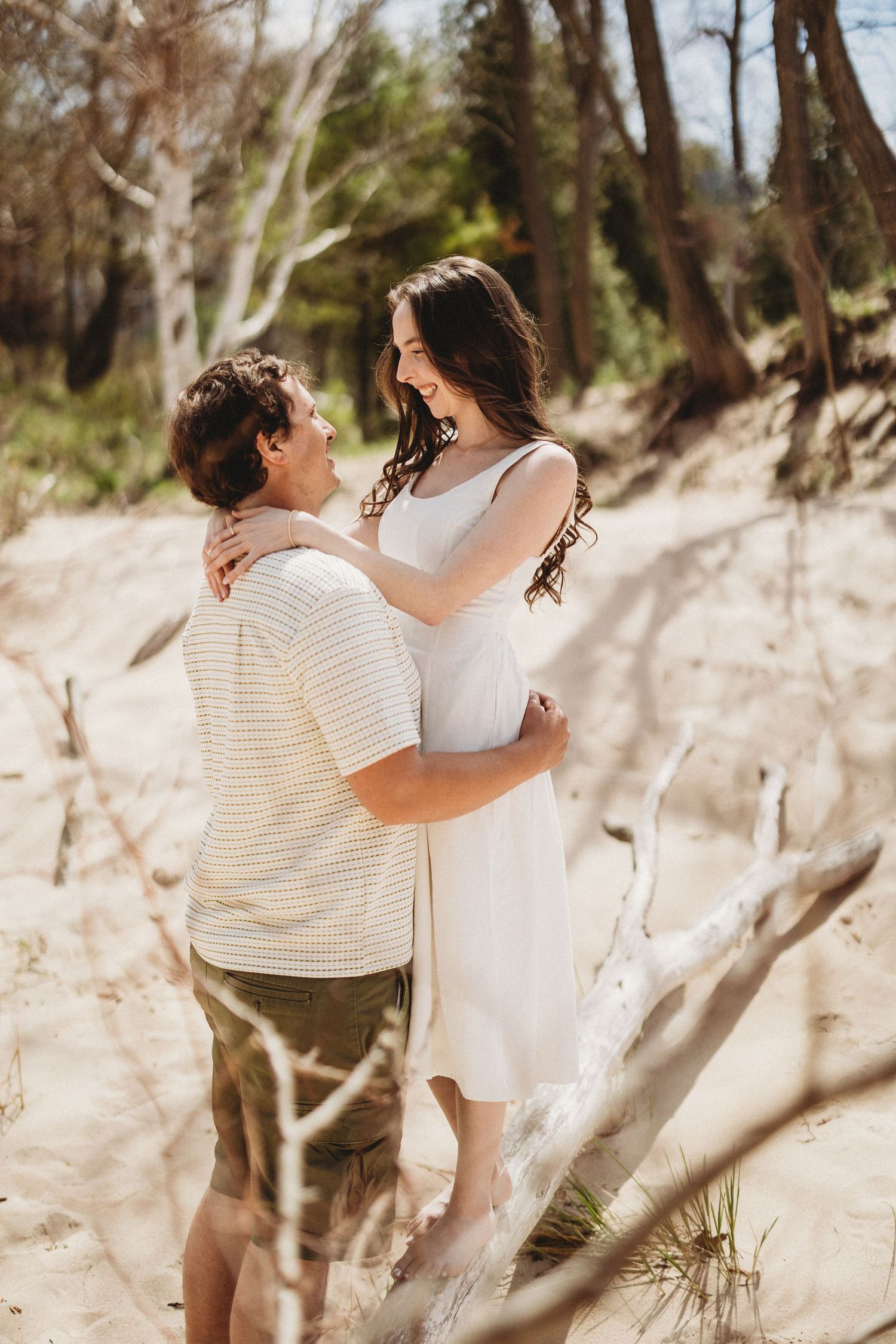 Romantic beach photoshoot among trees and dunes in natural lighting.
