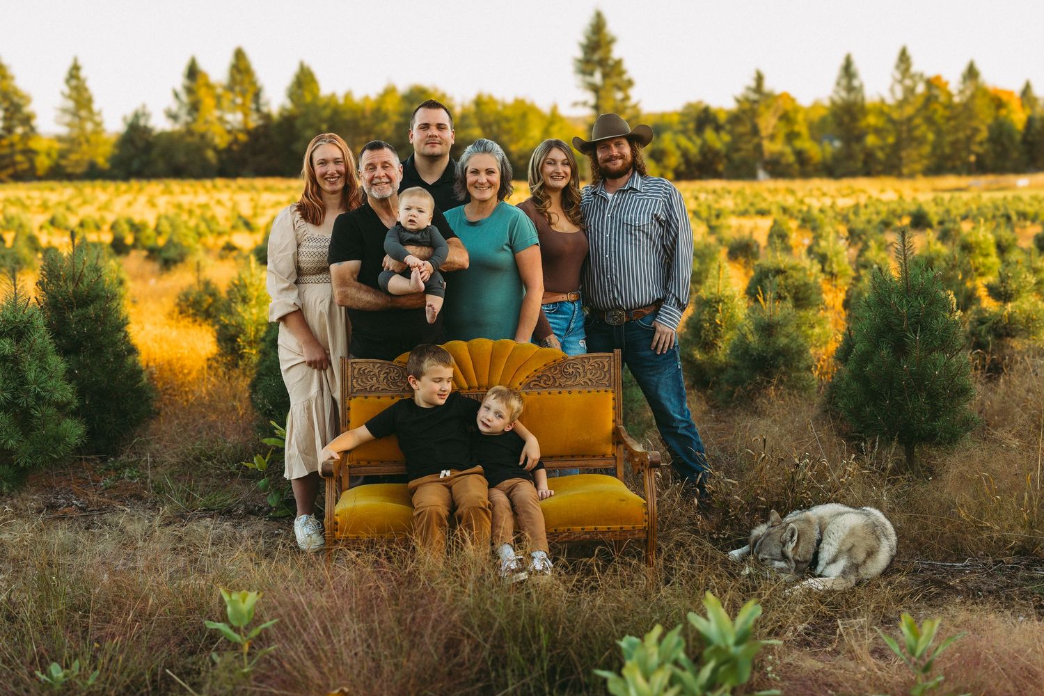 Family sitting together on yellow couch in outdoor autumn setting with golden sunlight.