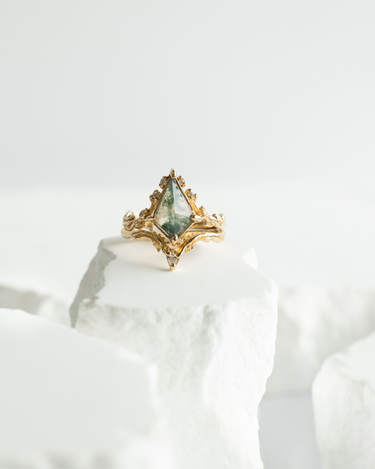 Gold vintage-style ring with sea green stone photographed on white crystalline surface.