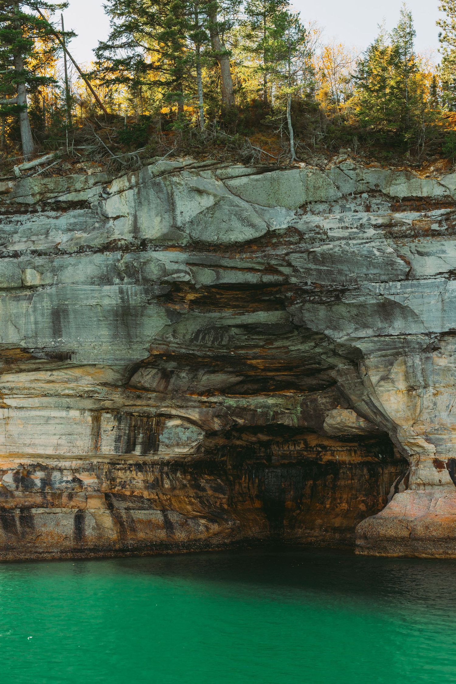Weathered limestone cliffs with distinct geological layers towering over vibrant turquoise waters.