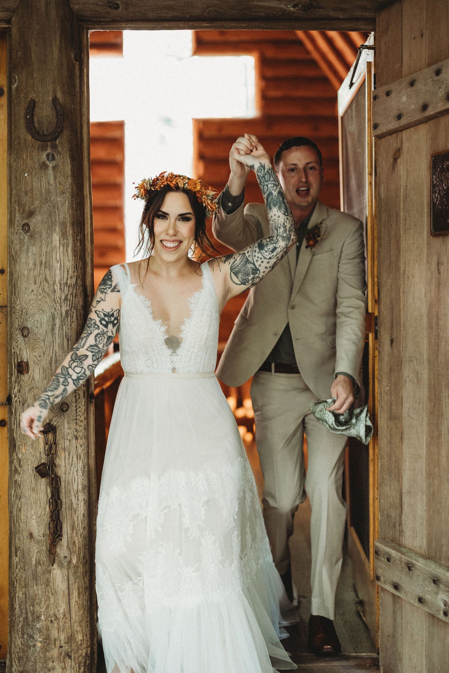 Joyful couple in wedding attire sharing a candid moment together in a rustic wooden barn setting.