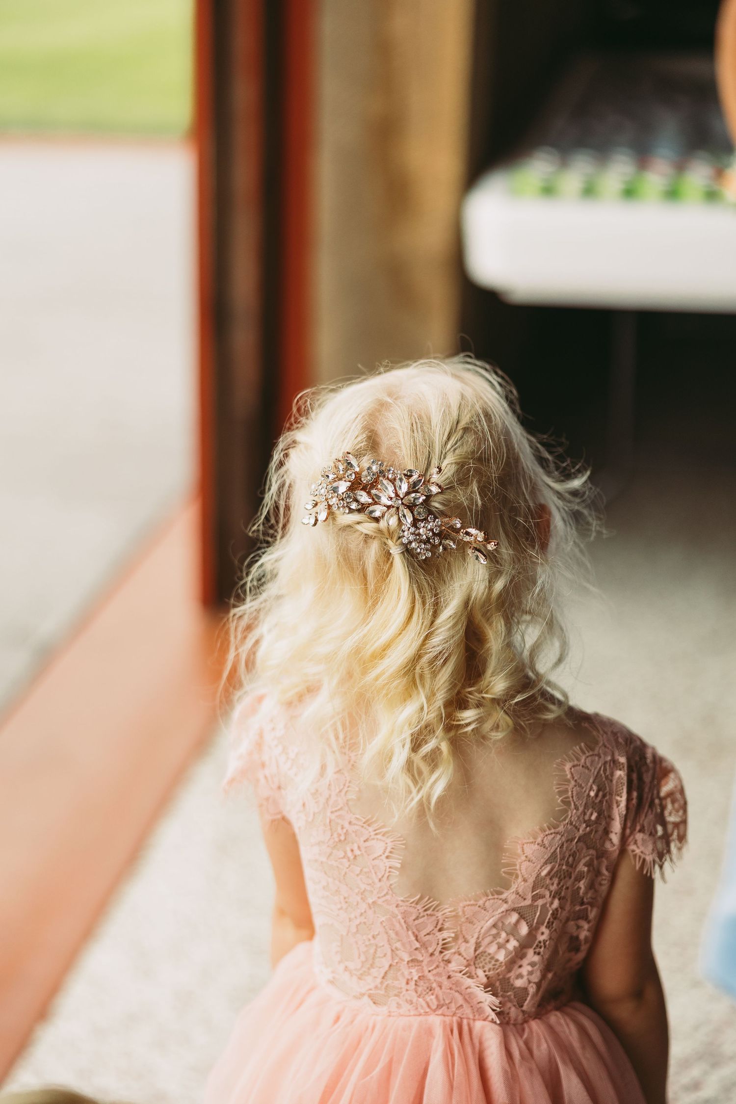 A delicate floral hair accessory adorns a pink dress in a soft, romantic wedding detail shot.