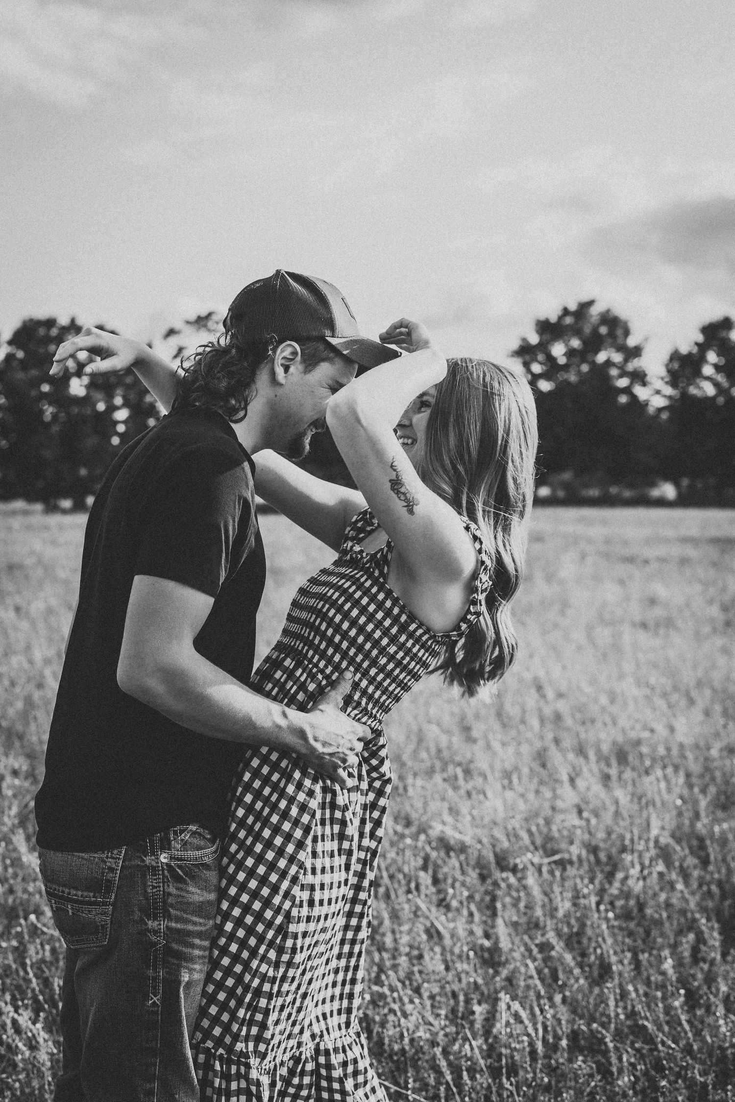Black and white photo of couple embracing in a rural field.