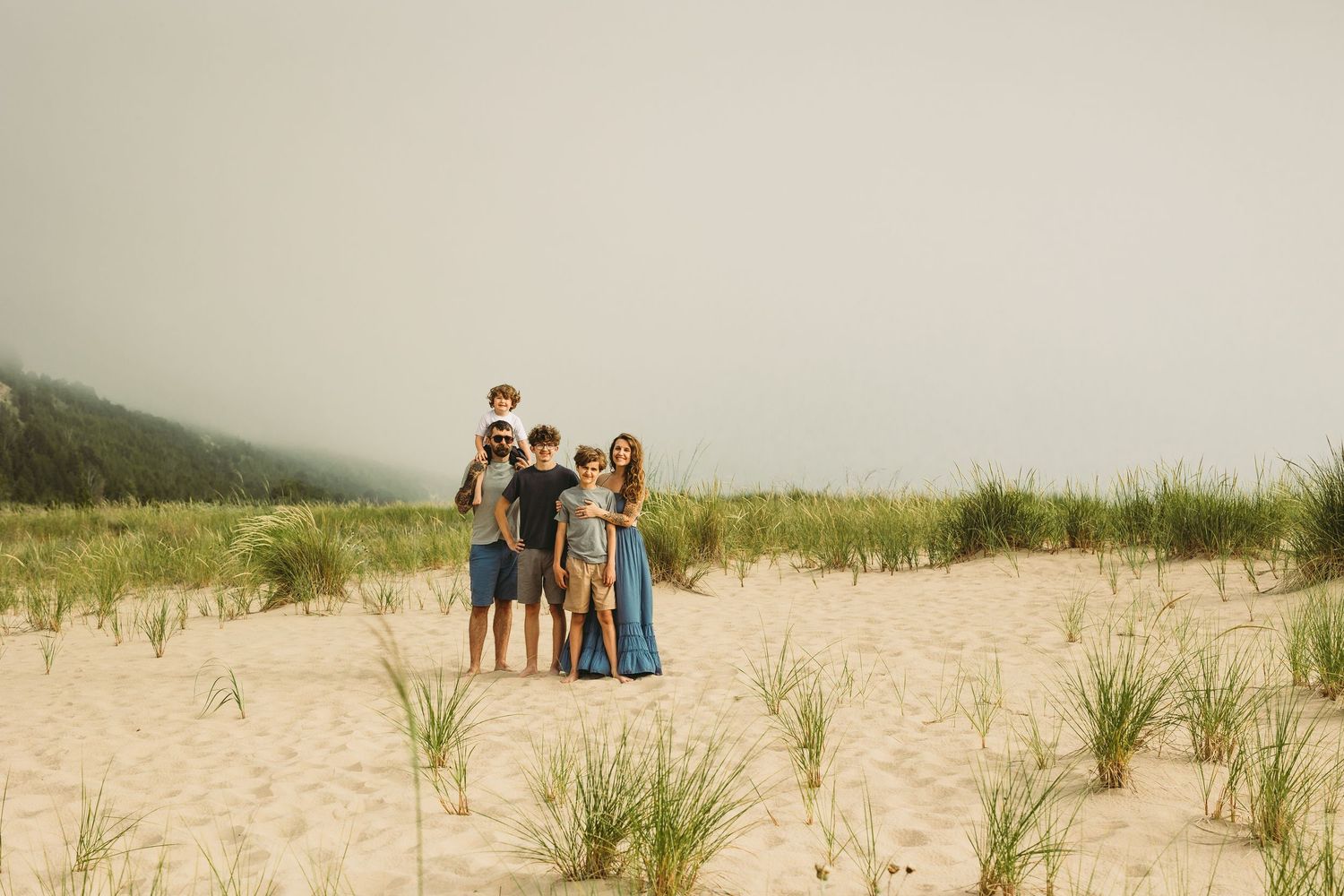 A family portrait taken against misty dunes and beach grass.