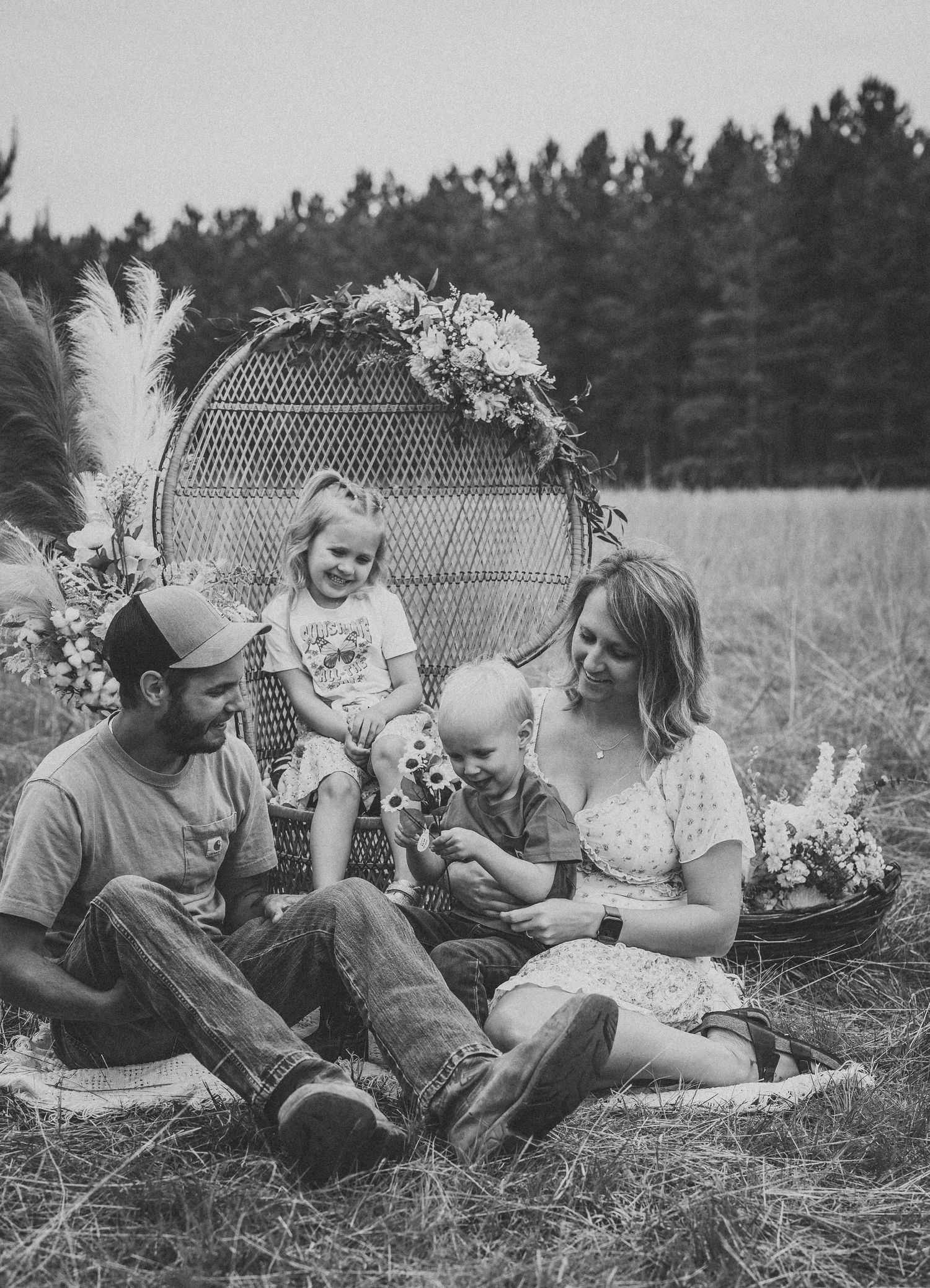 Black and white family portraits show intimate moments on a woven peacock chair in nature.