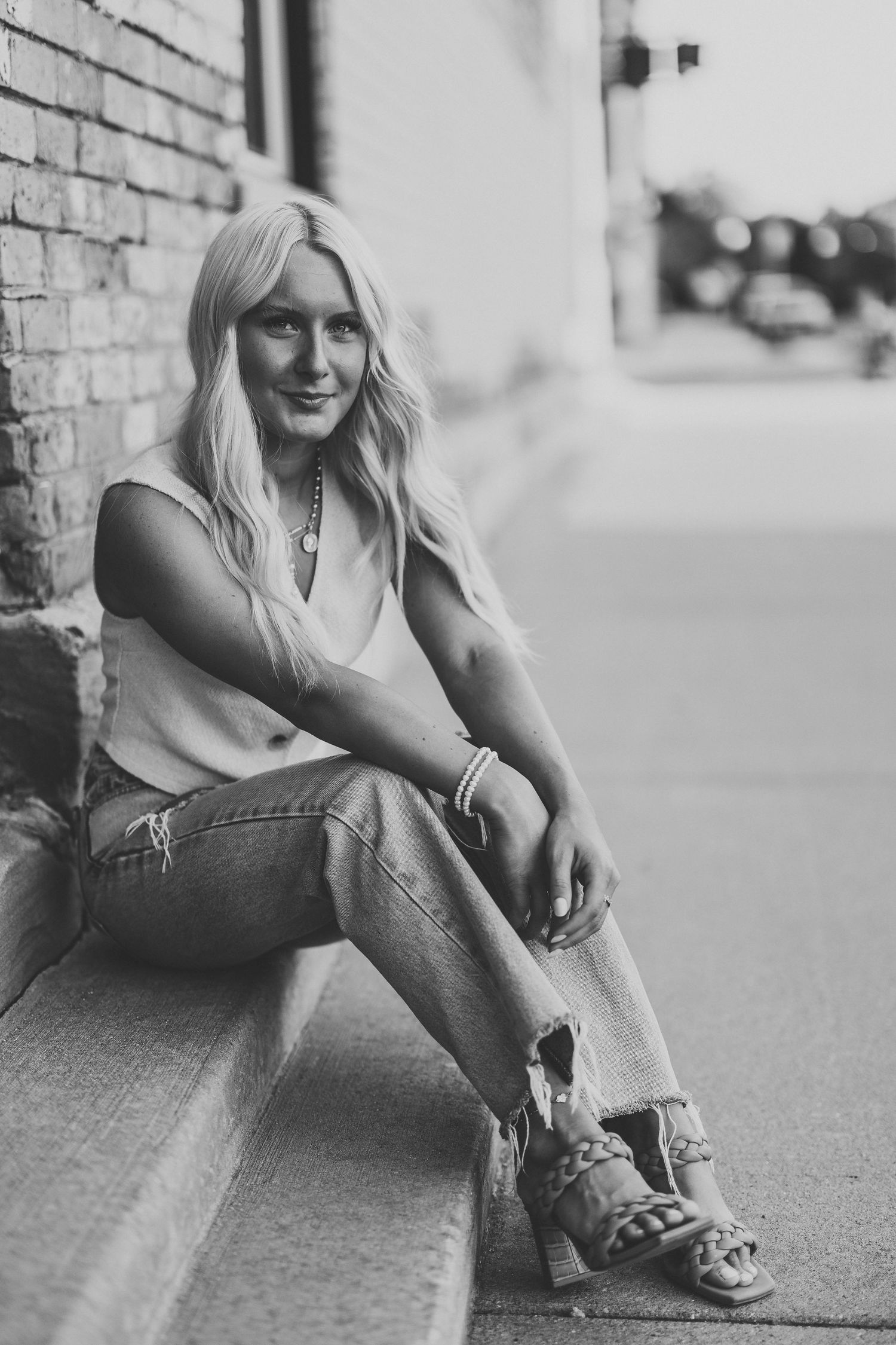 Relaxed lifestyle portraits sitting against an urban brick wall wearing casual denim.