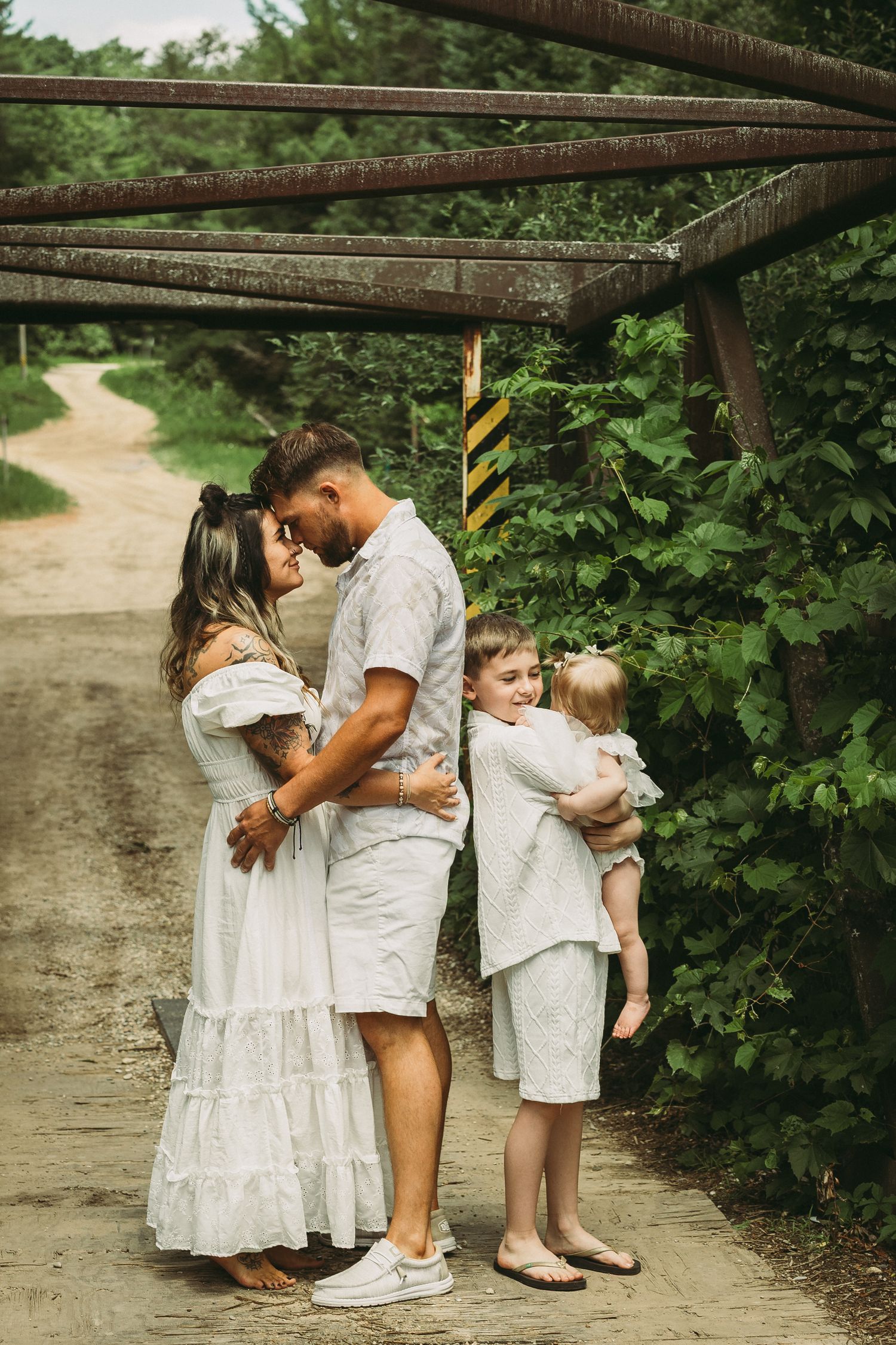 Family dressed in white outfits sharing tender moments together on a garden path.