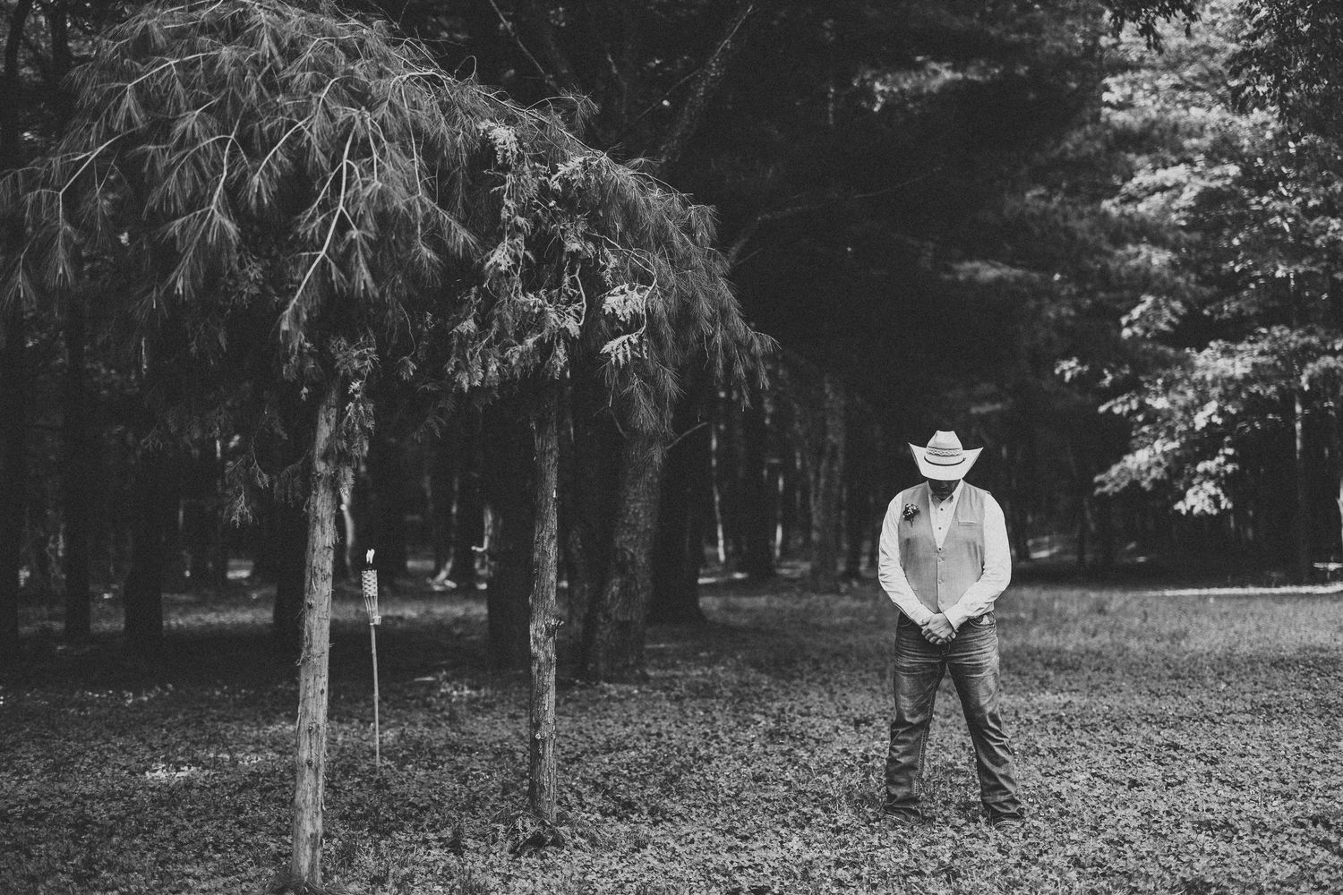 Black and white outdoor portrait session in a wooded area with evergreen trees.