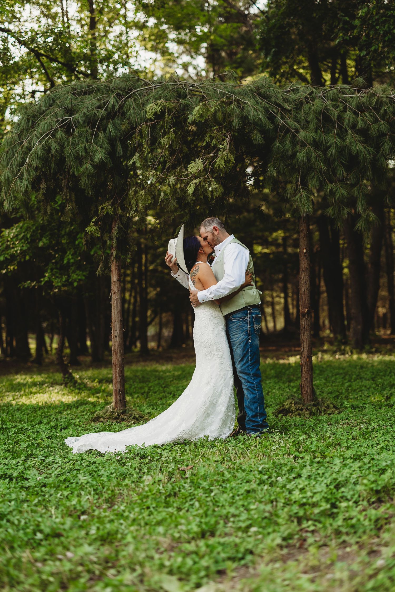 A couple shares an intimate moment in a lush green forest setting during their wedding photoshoot.