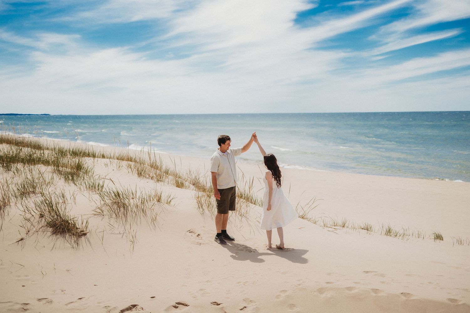 A group walks along a scenic beach path with sand dunes and blue skies on a sunny summer day.