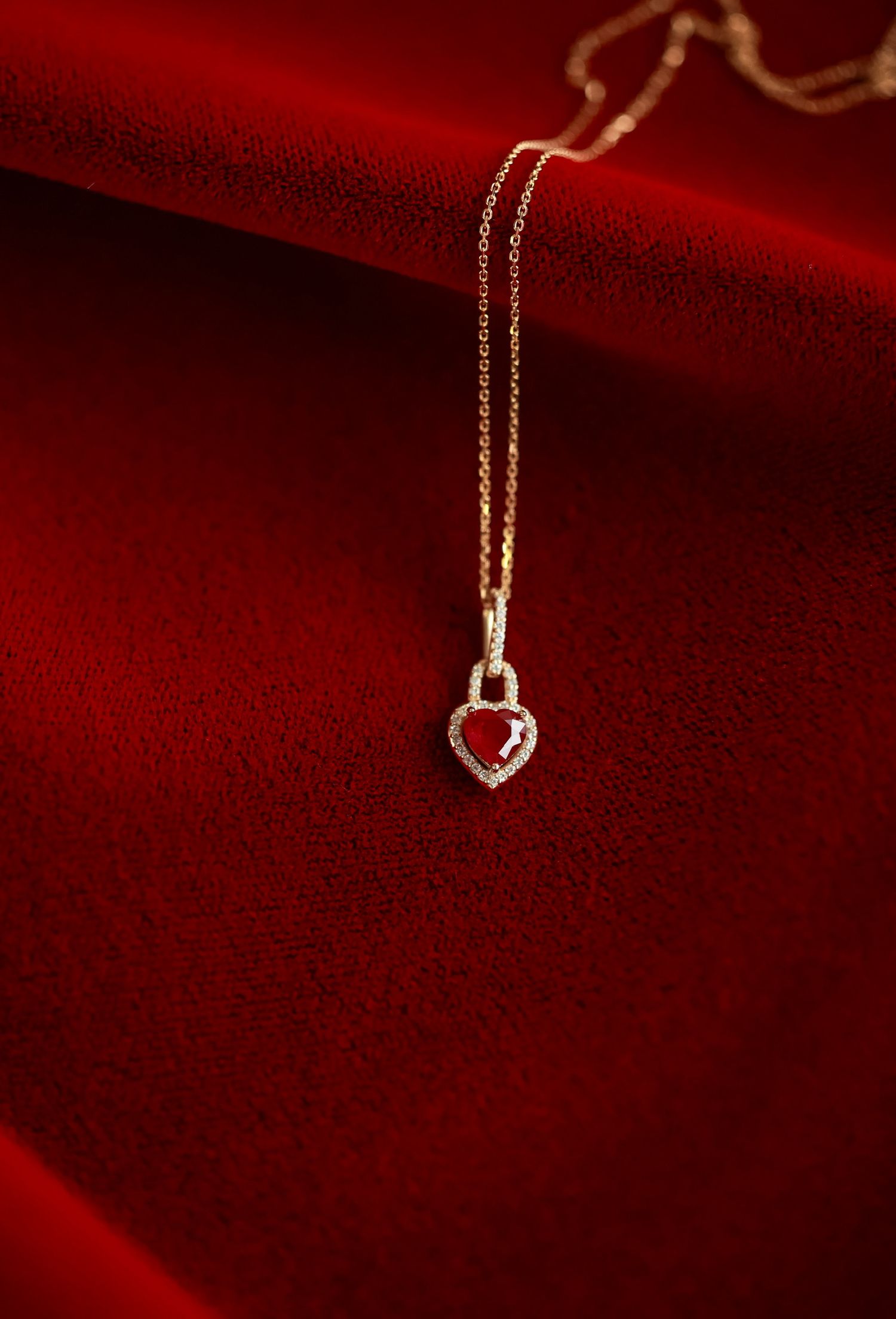 Delicate gold arrow pendant necklace displayed on red velvet background.