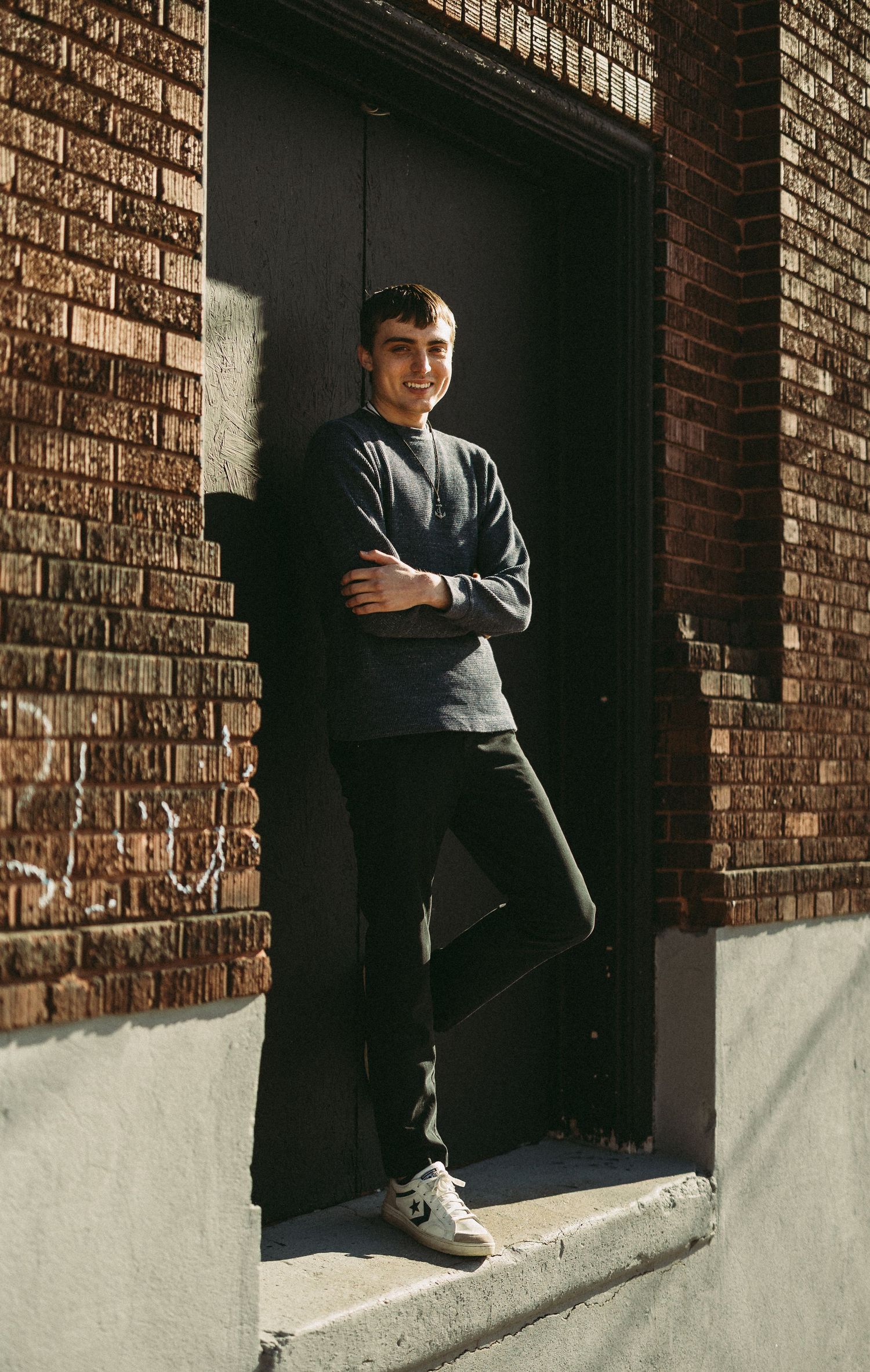 Portrait session against brick wall featuring casual poses in urban setting.