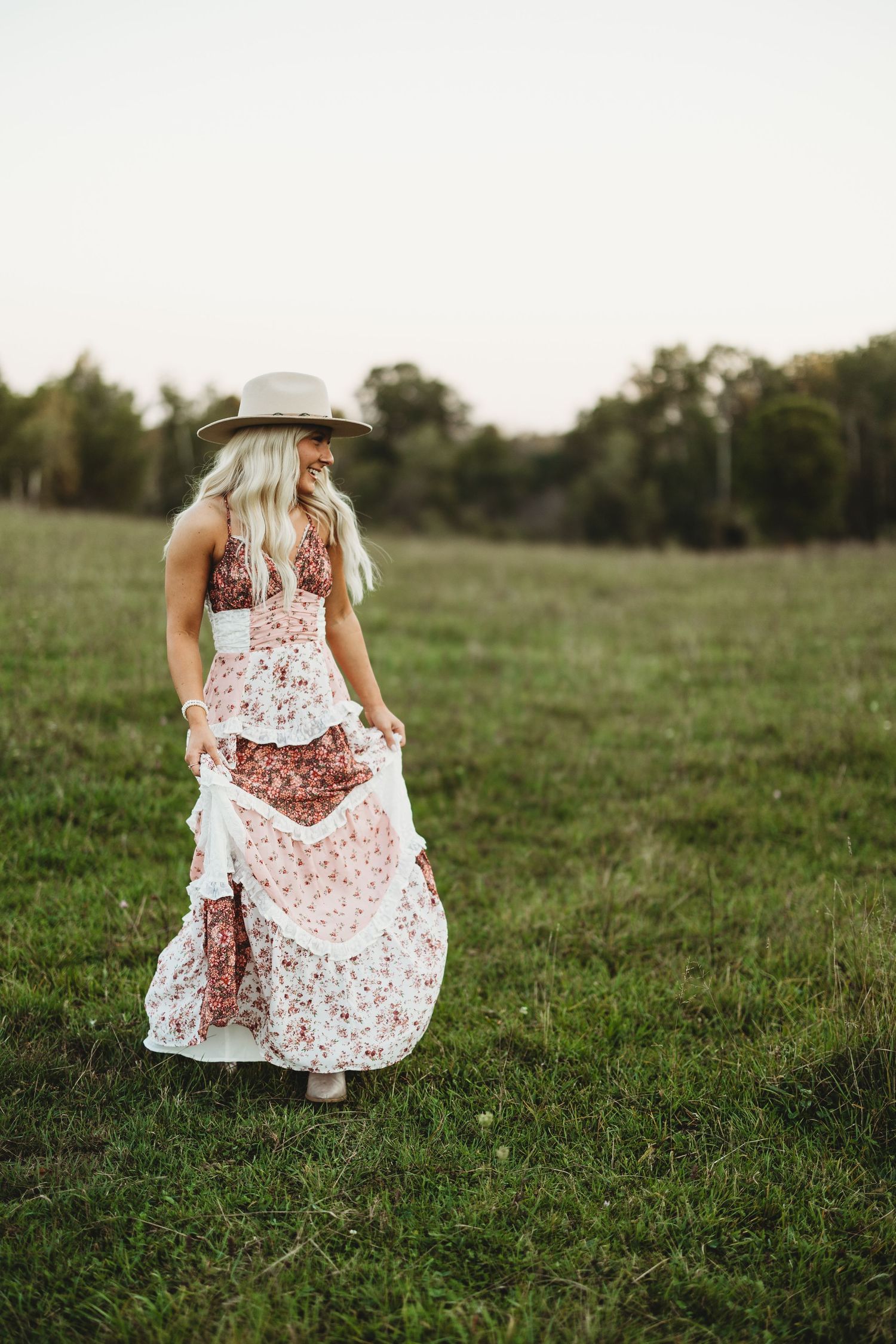 Twirling in a white and pink floral dress in a green summer meadow.