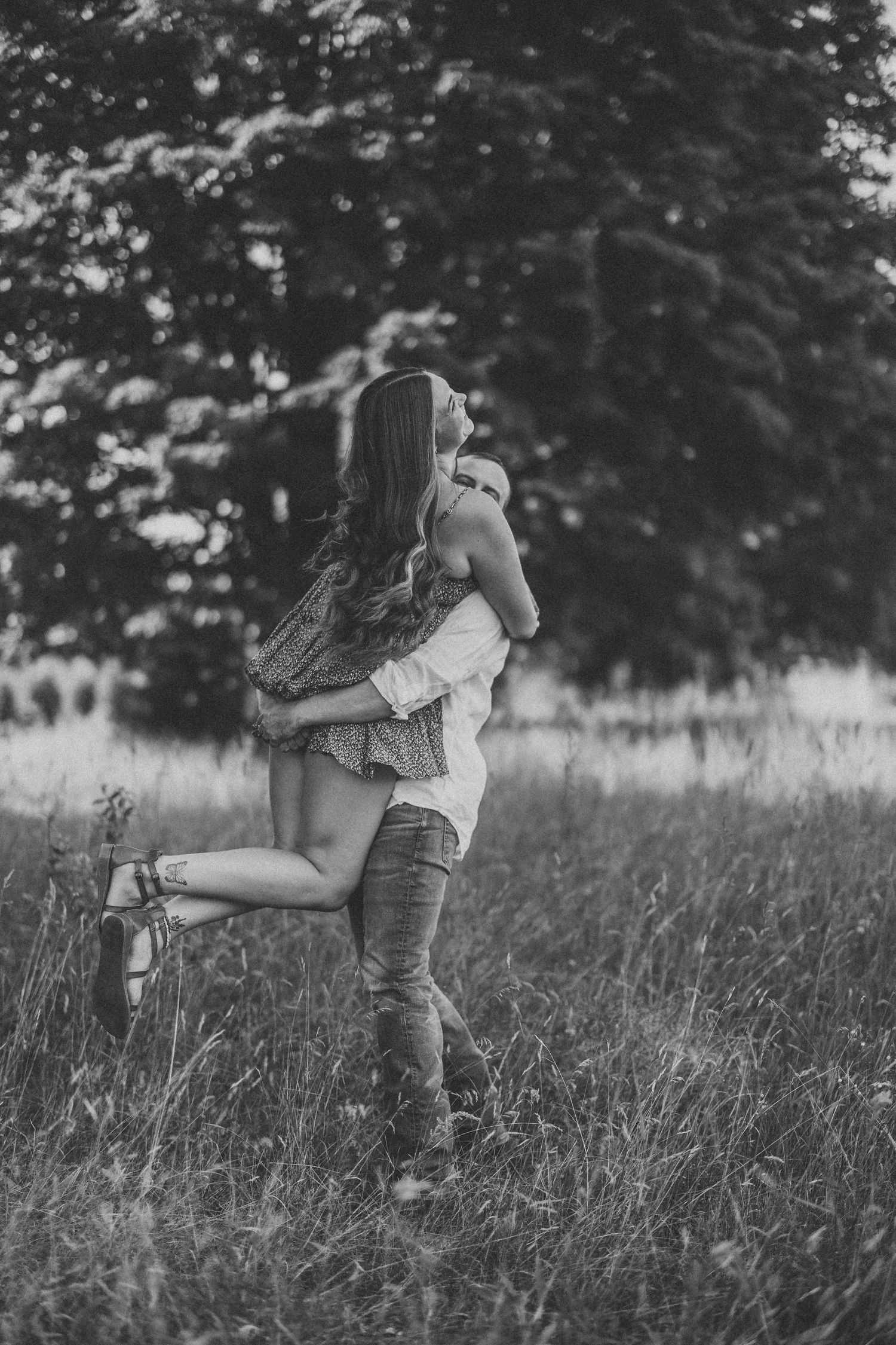 Romantic couple embraces in a tall grass field during golden hour photography session.