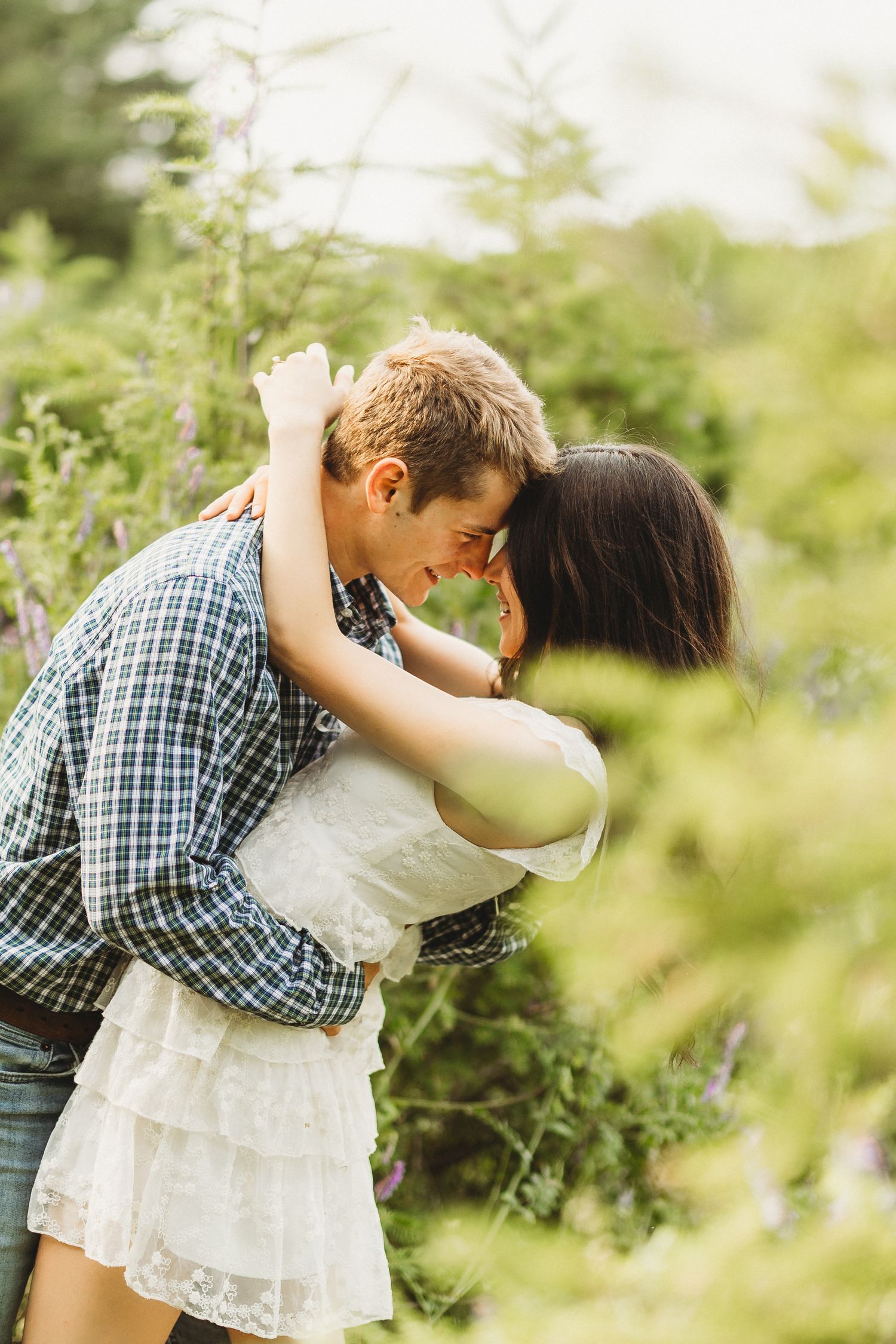 A couple shares intimate moments in a series of romantic outdoor photos with green foliage in the background.